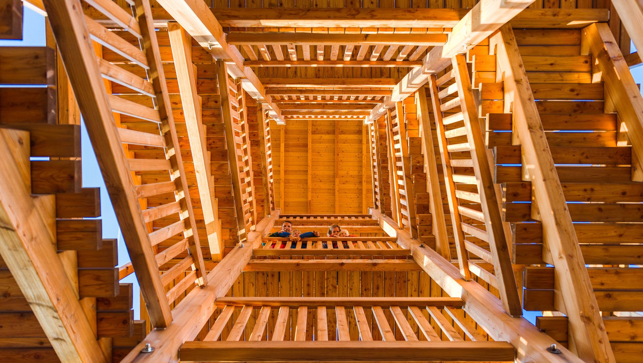 View from below into a wooden observation tower with several levels and stairs.
