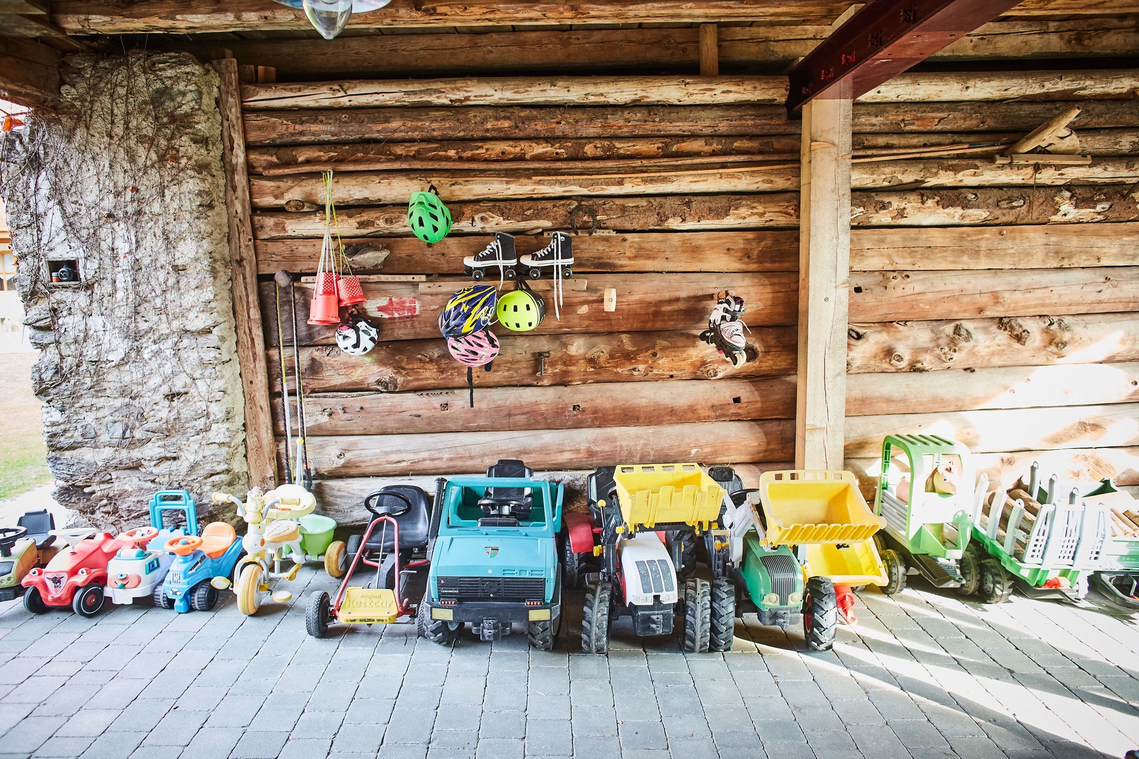 Toy vehicles and helmets in a woodshed.