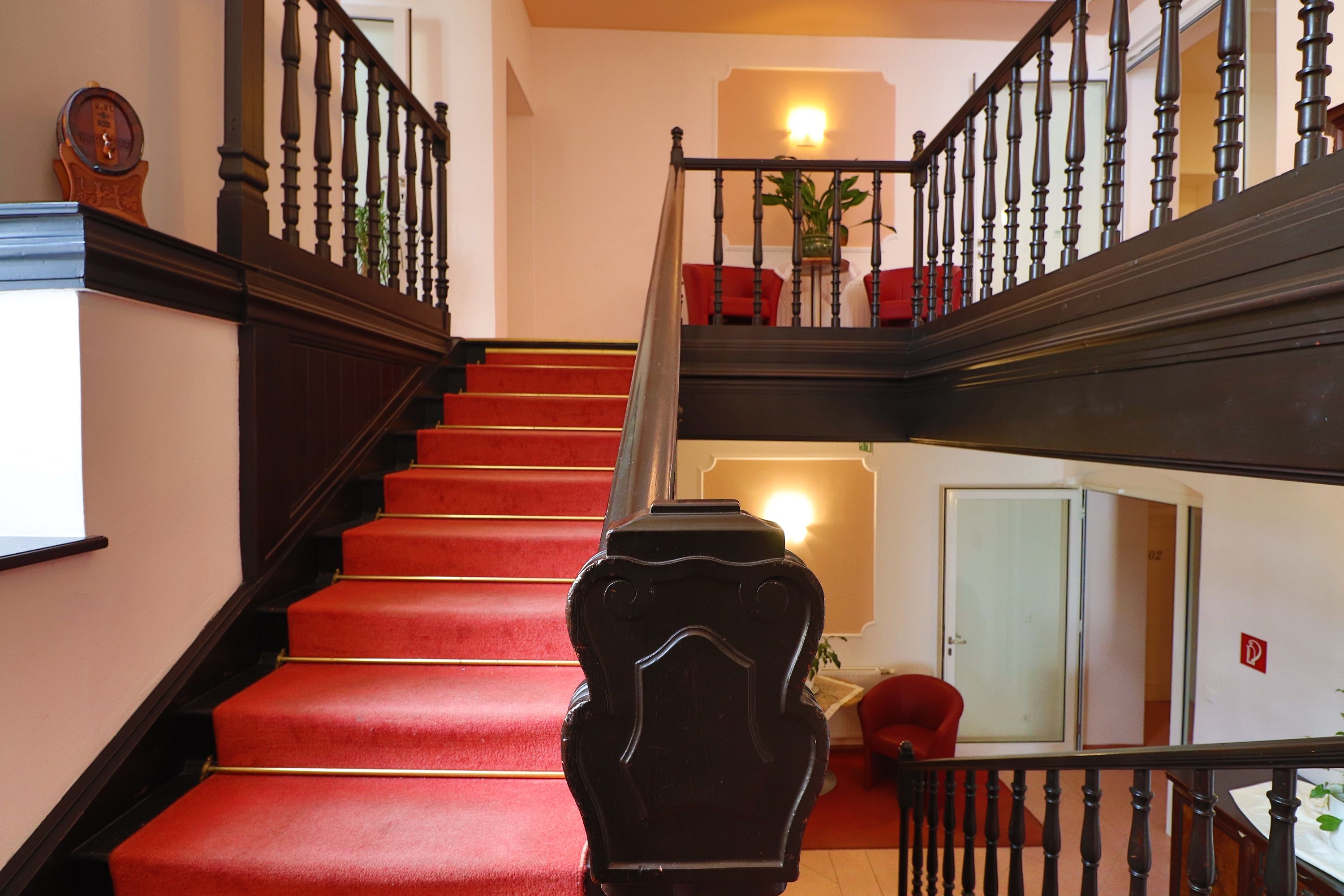 Hotel staircase with red carpet and dark wooden banister.