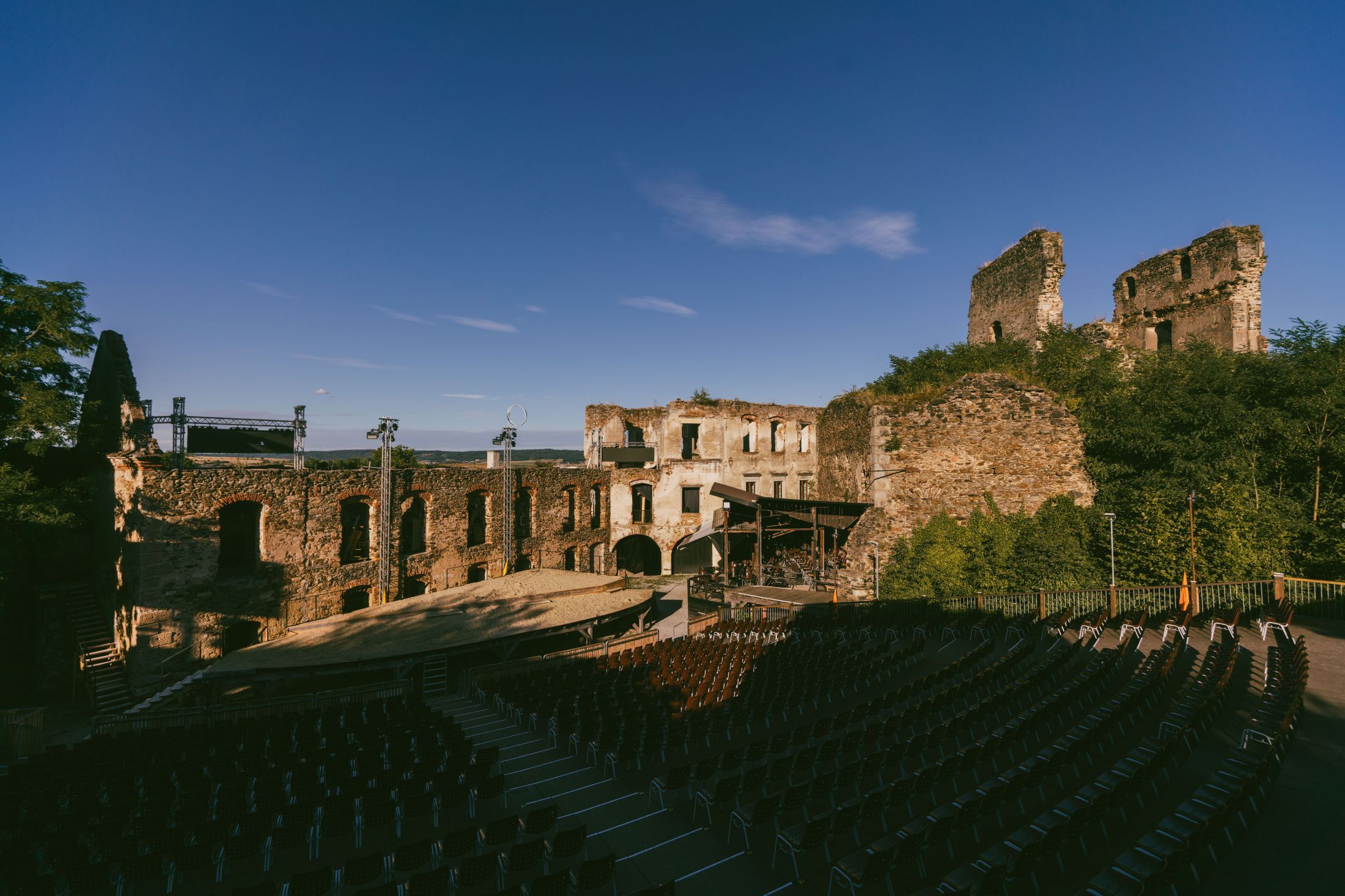 Ruins of Gars Castle with open-air stage and rows of seats.