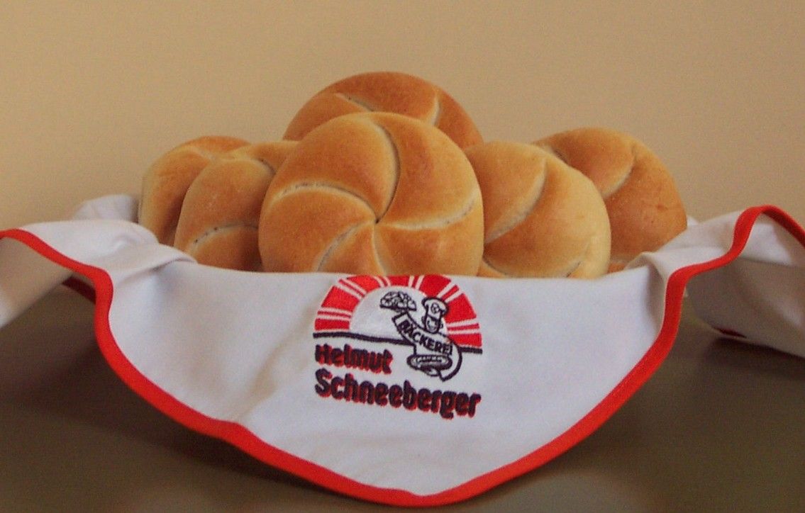 A basket of fresh bread rolls, covered with a napkin from the Helmut Schneeberger bakery.