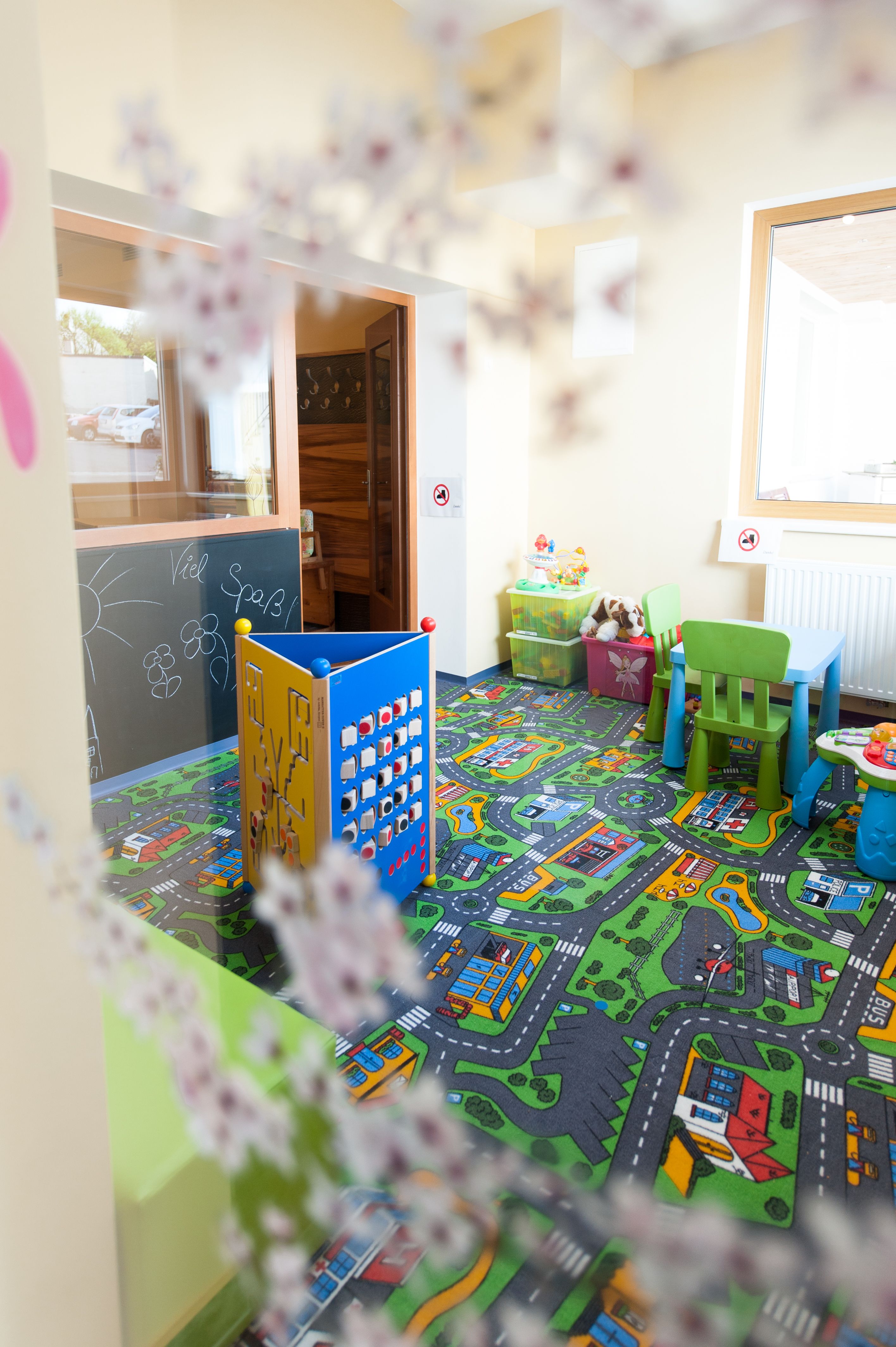 A colorful children's playroom with carpet, toys and small furniture.