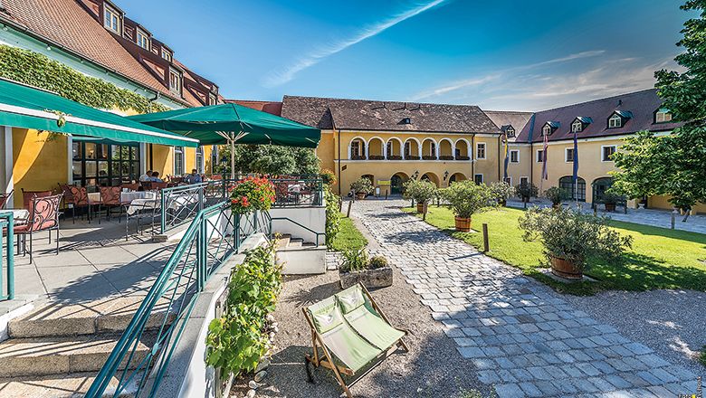 Inner courtyard of the Althof Retz with terrace, parasols and garden.