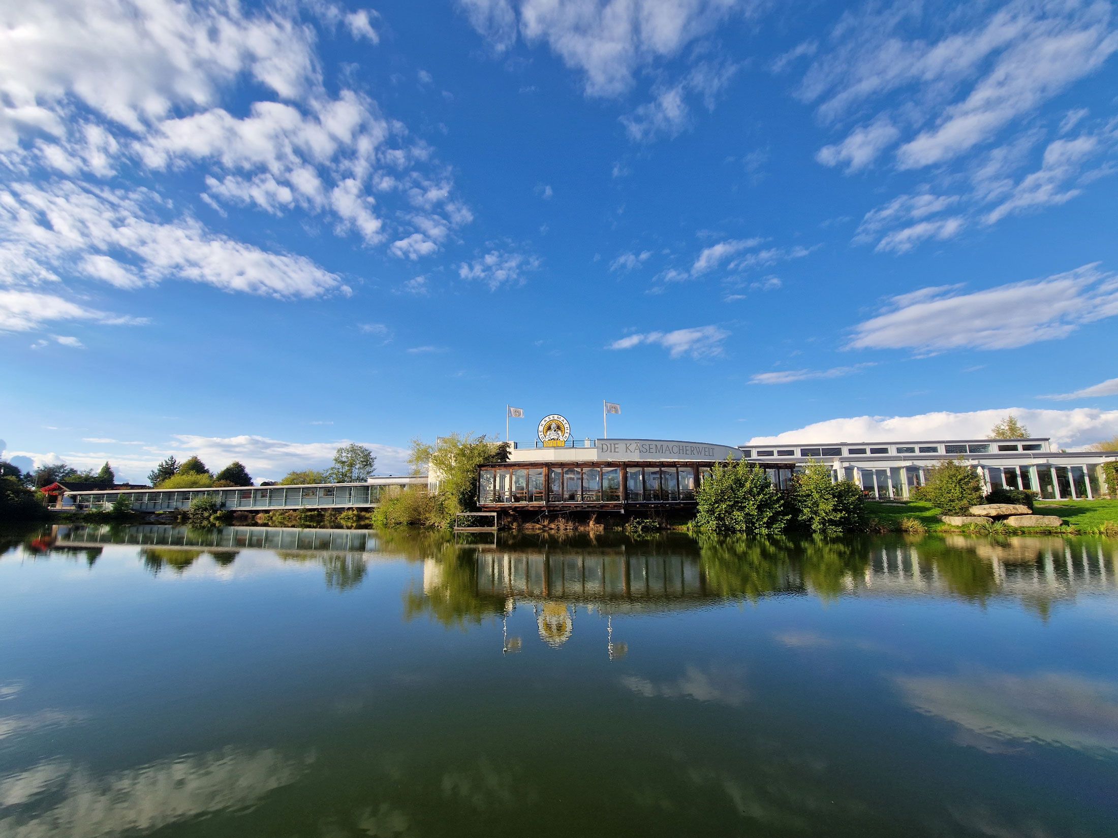Exterior view of the cheese maker's world with blue sky and lake in the foreground.