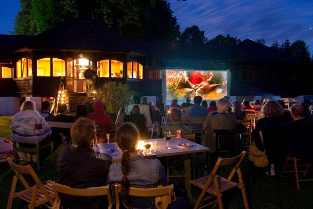 People watch a movie on a screen outdoors.