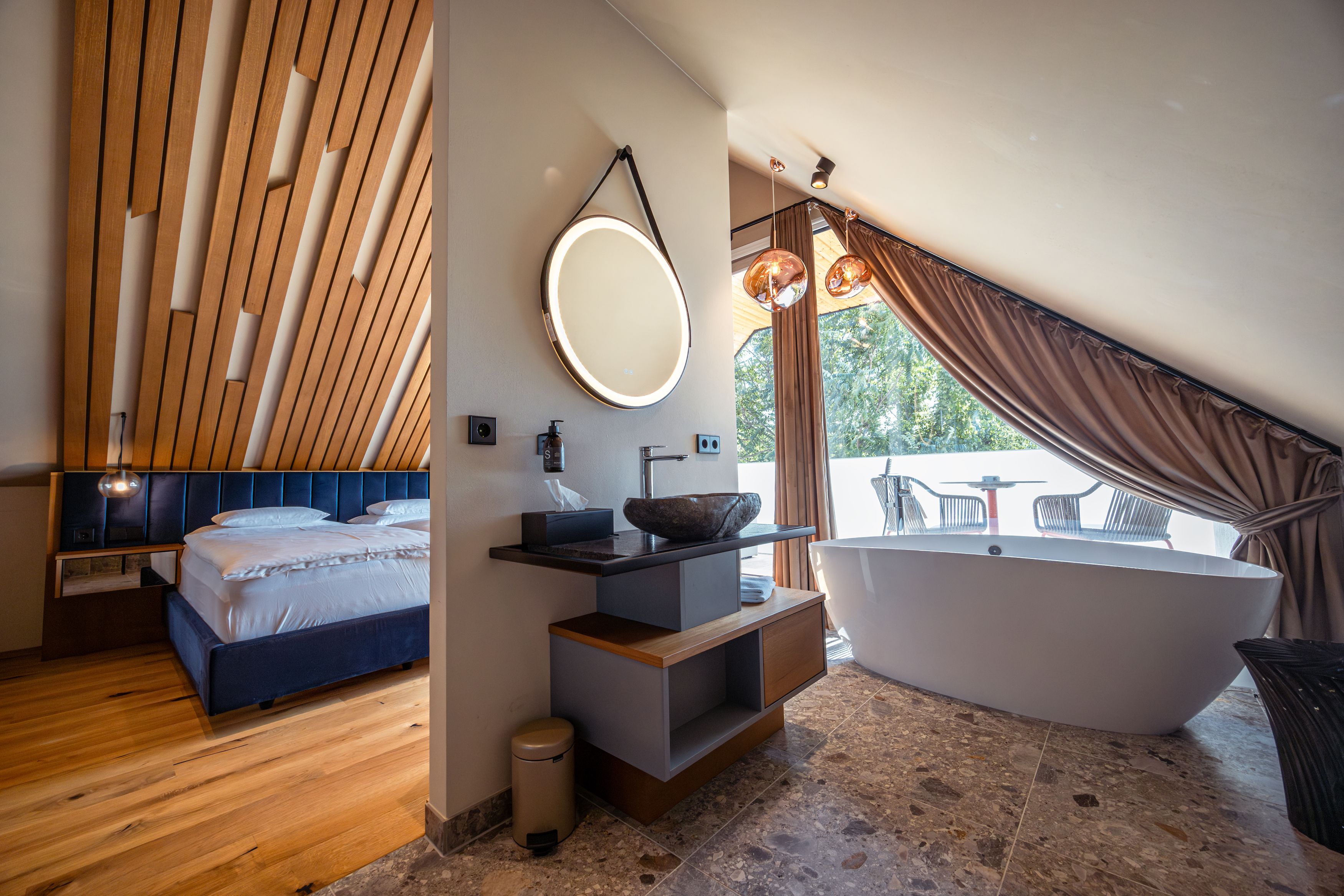 Modern hotel room with wooden ceiling, free-standing bathtub and balcony.