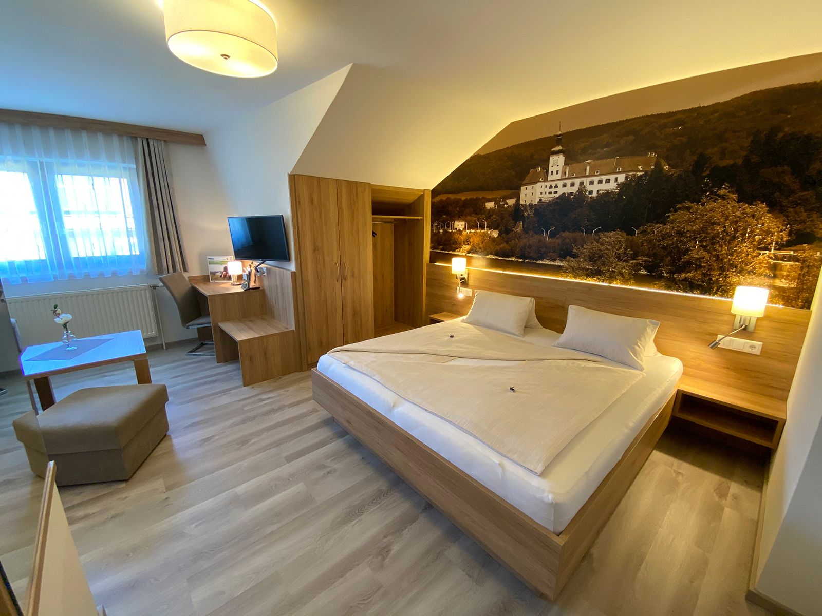 Modern hotel room with double bed, desk, TV and large mural.