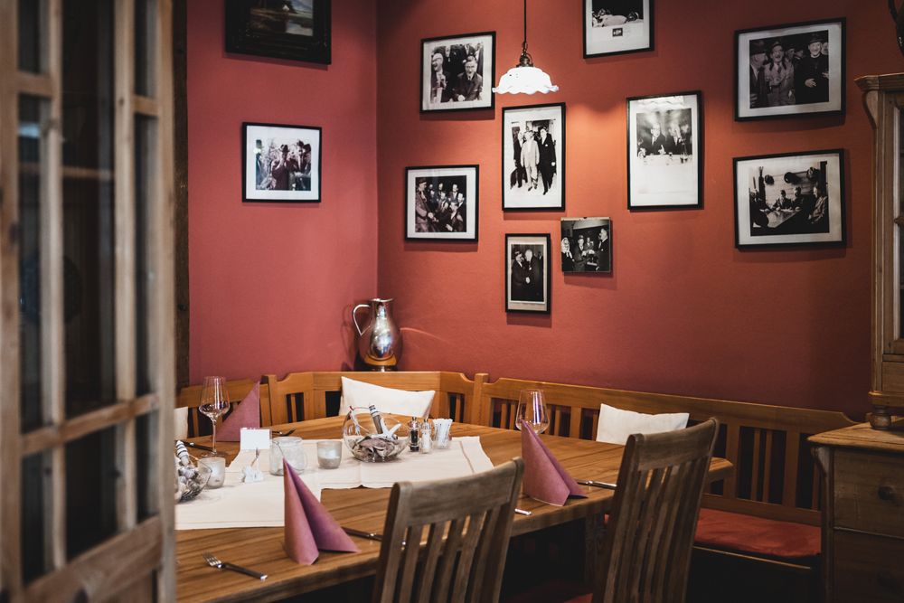 Cozy restaurant with wooden table, red walls and framed photos.