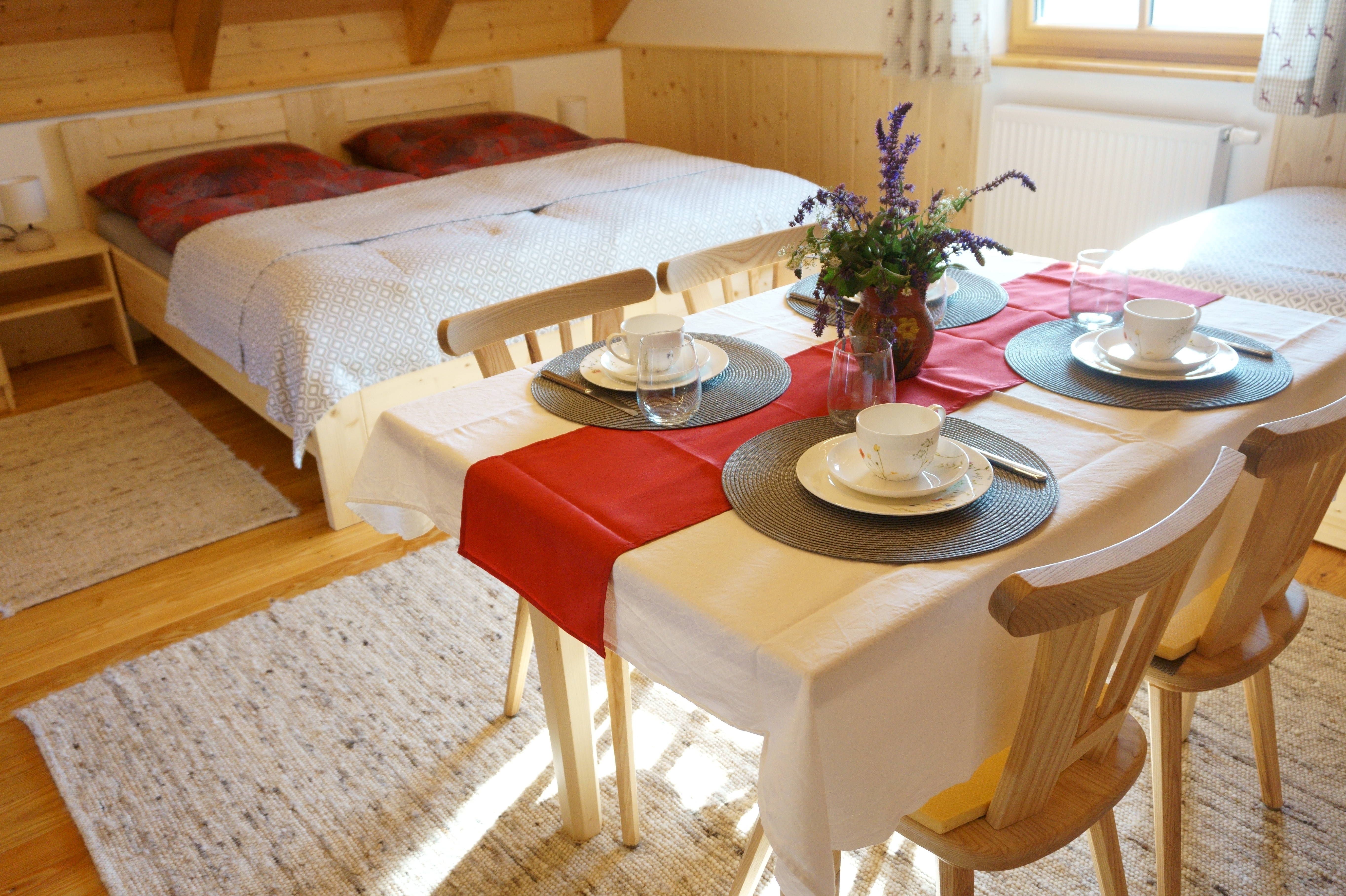 Cozy room with double bed and dining table, set for four people.