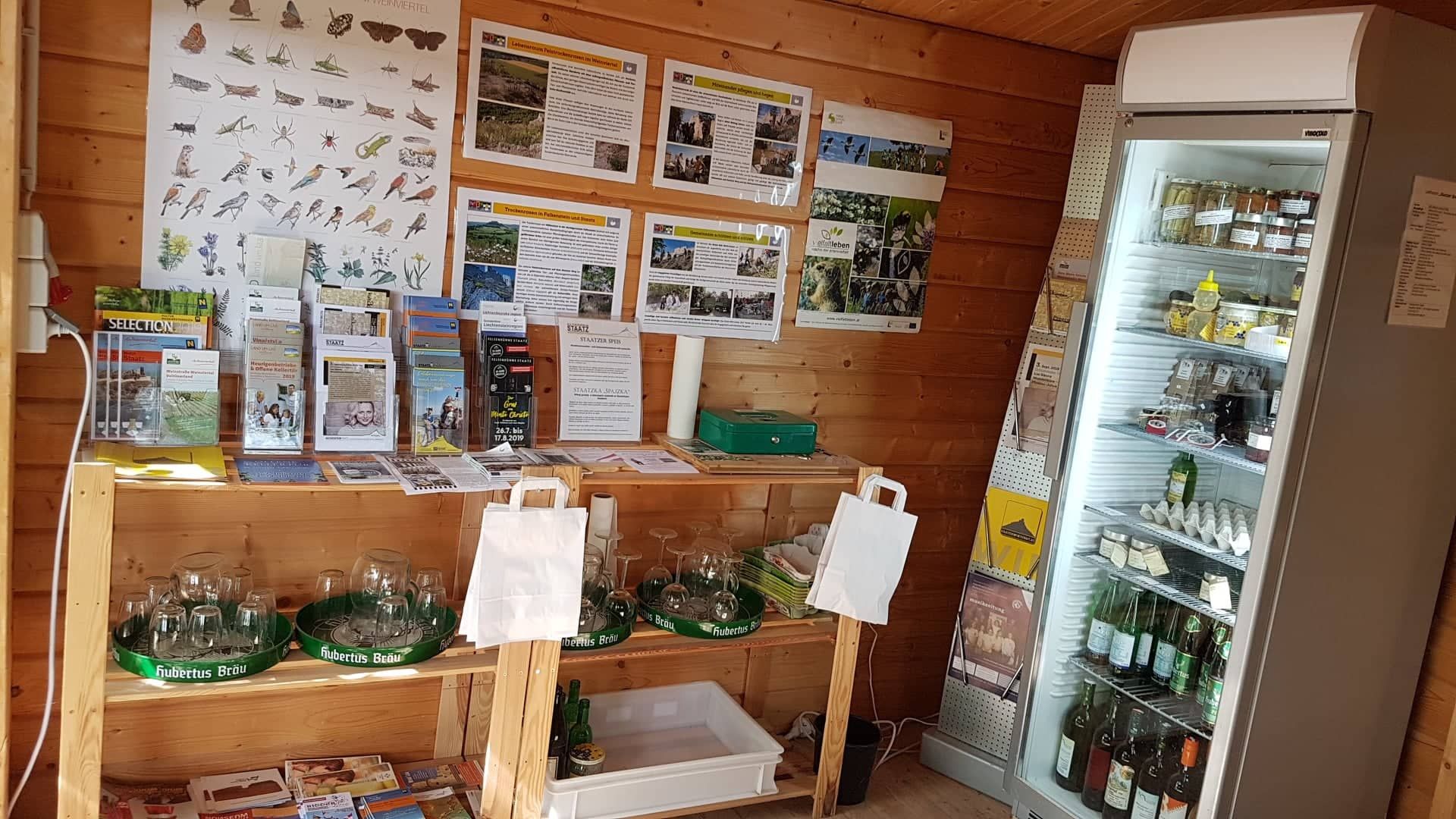 Interior view of a small sales stand with information material and refrigerator.