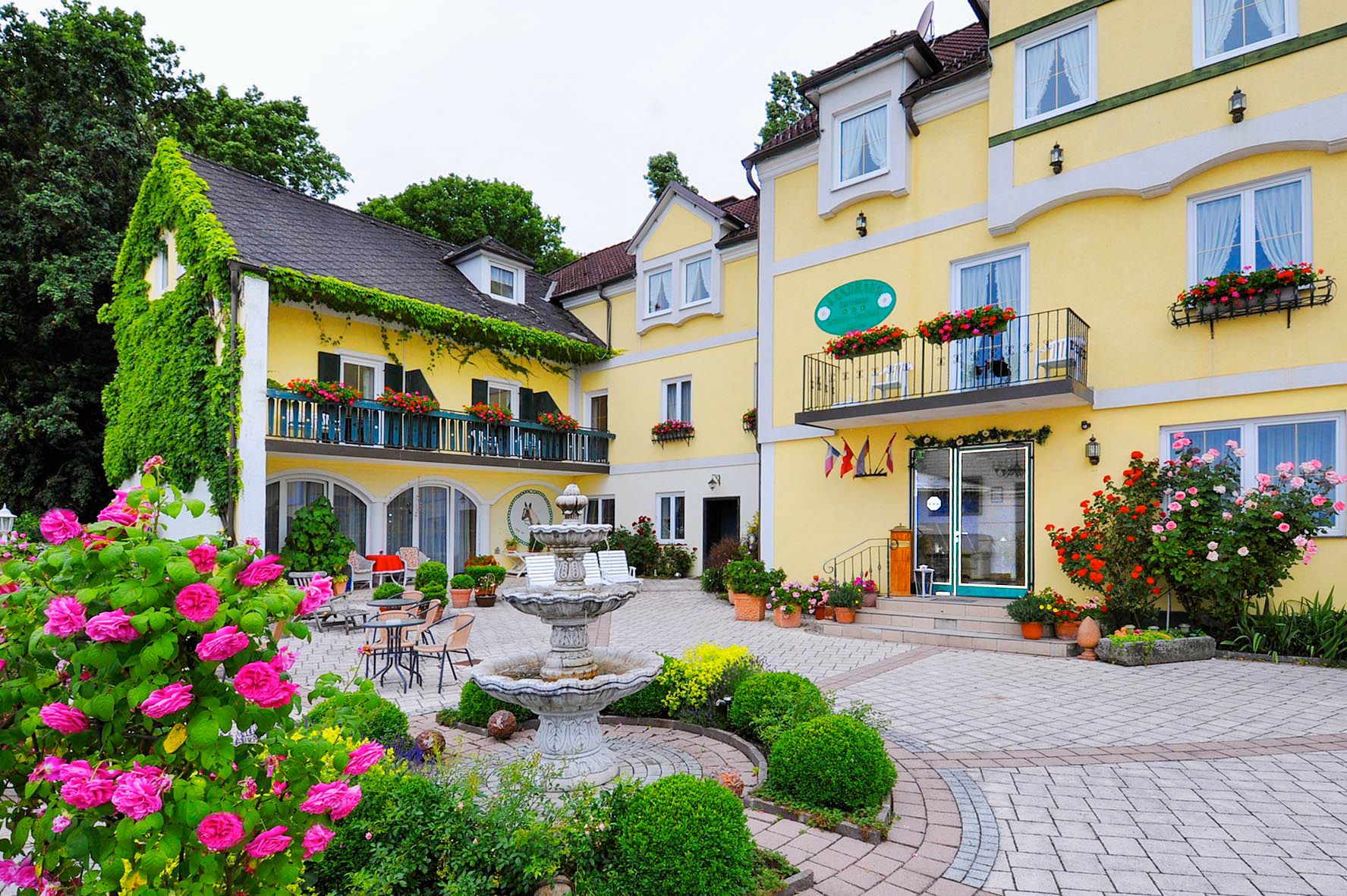 Yellow hotel building with floral decorations and fountain in the foreground.