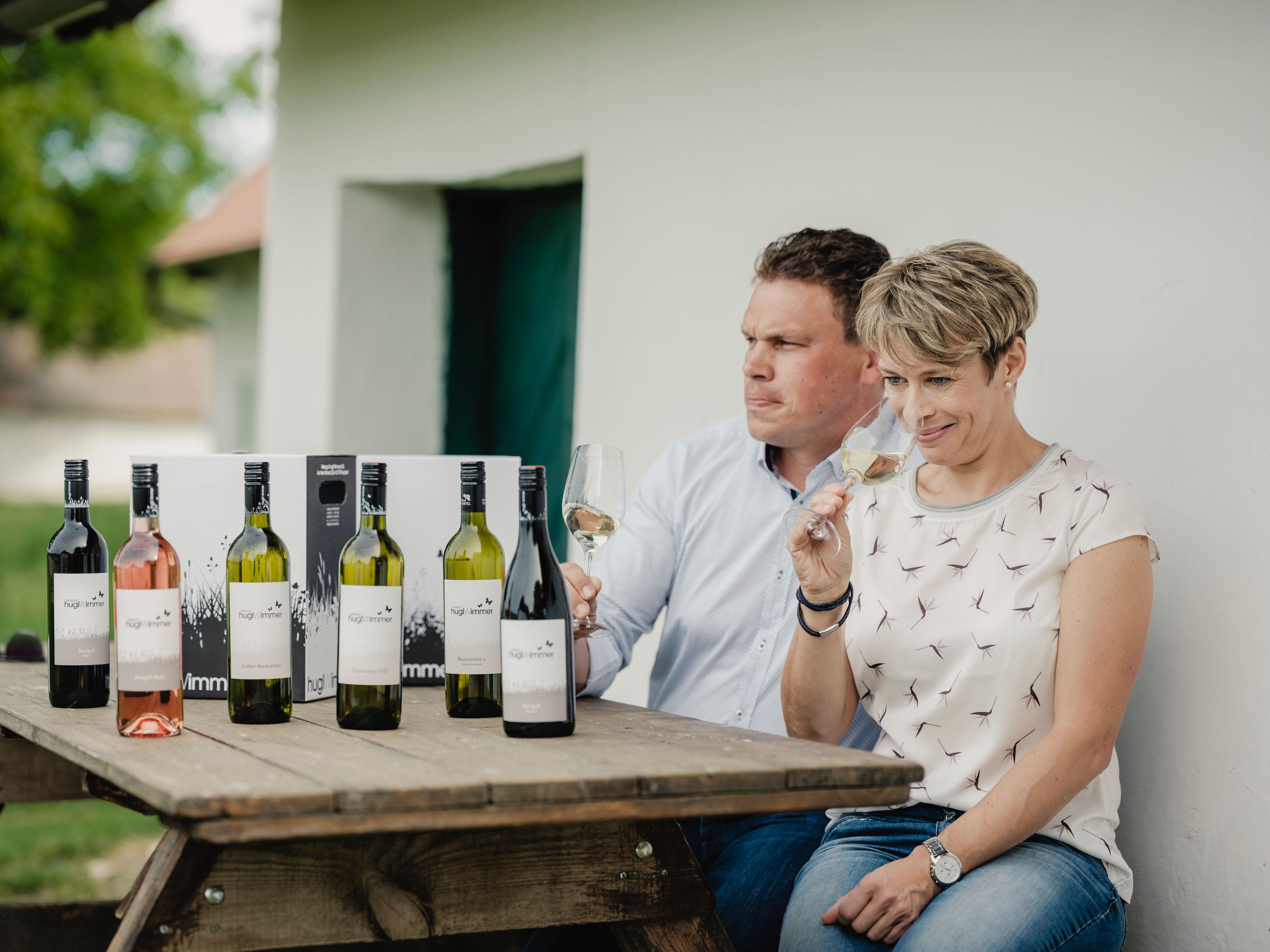 Two people are sitting at a table with bottles of wine and tasting wine.