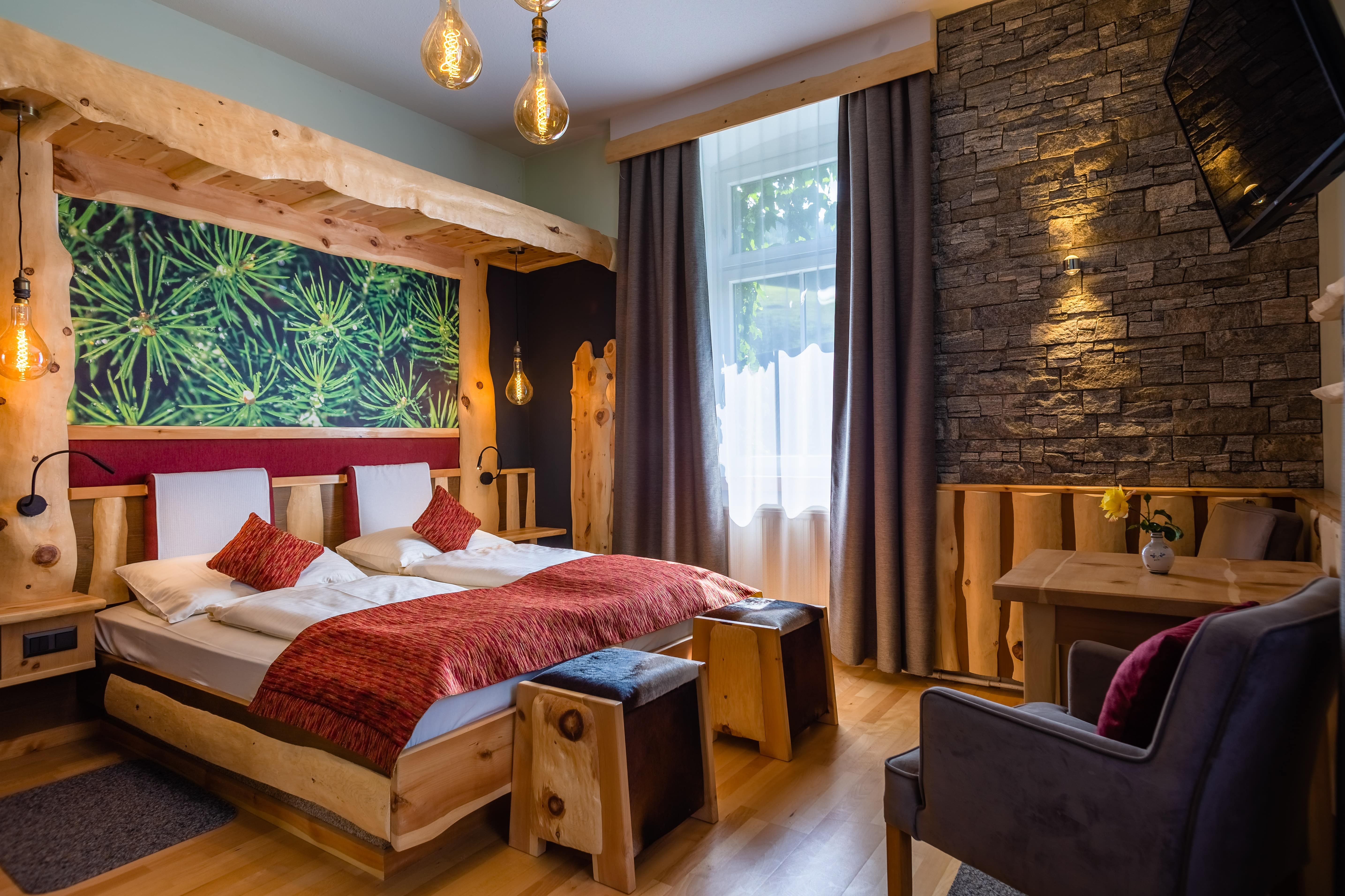 Cozy hotel room with wooden furniture, stone wall and large window.