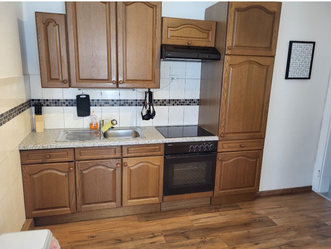 Kitchen with wooden cupboards, stove and sink.