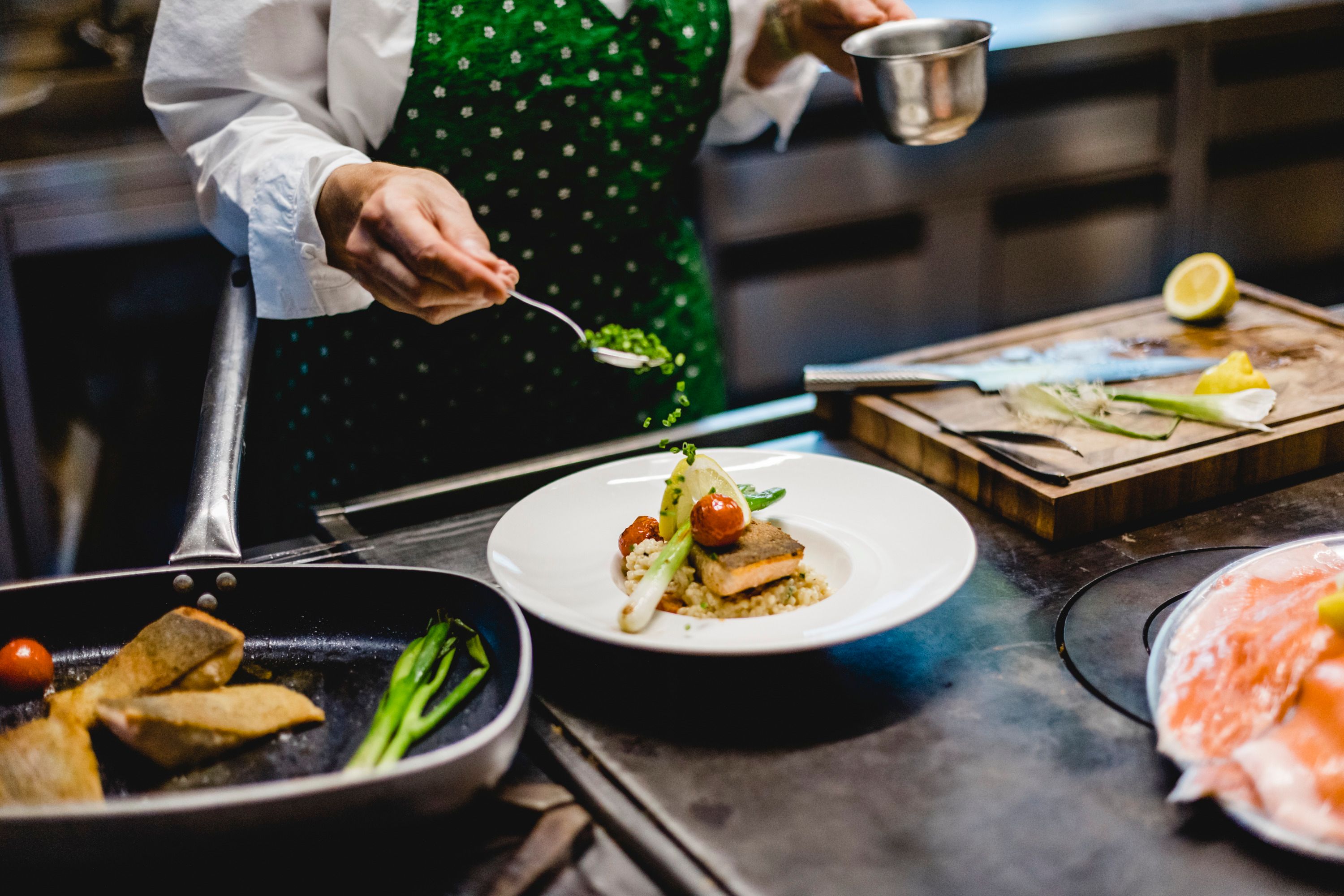 Chef decorates a dish with herbs in a kitchen.