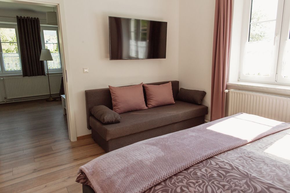 Modern living room with sofa, flat screen TV and window with pink curtains.