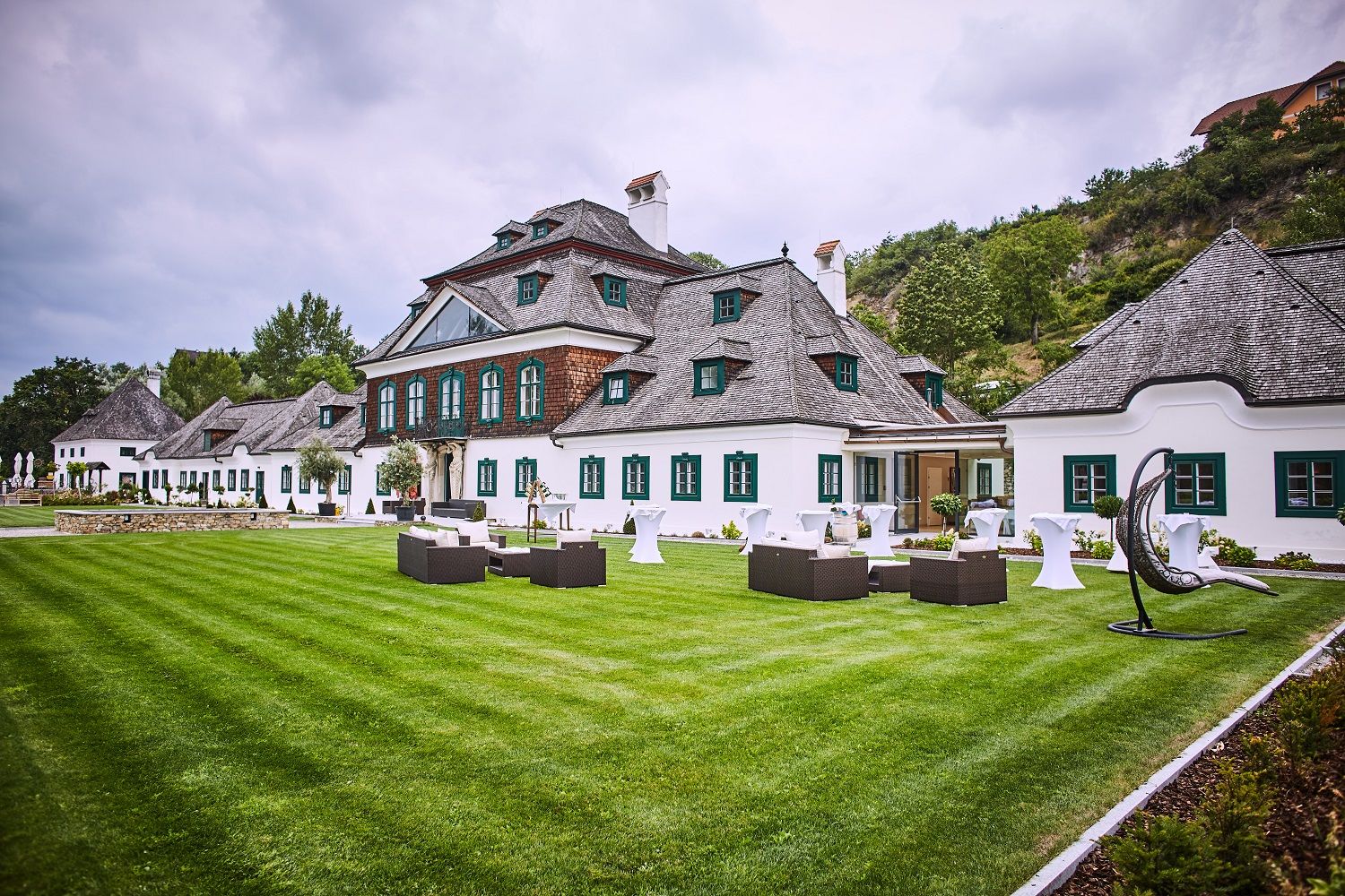 Schloss Luberegg with manicured lawn and garden furniture in the foreground.