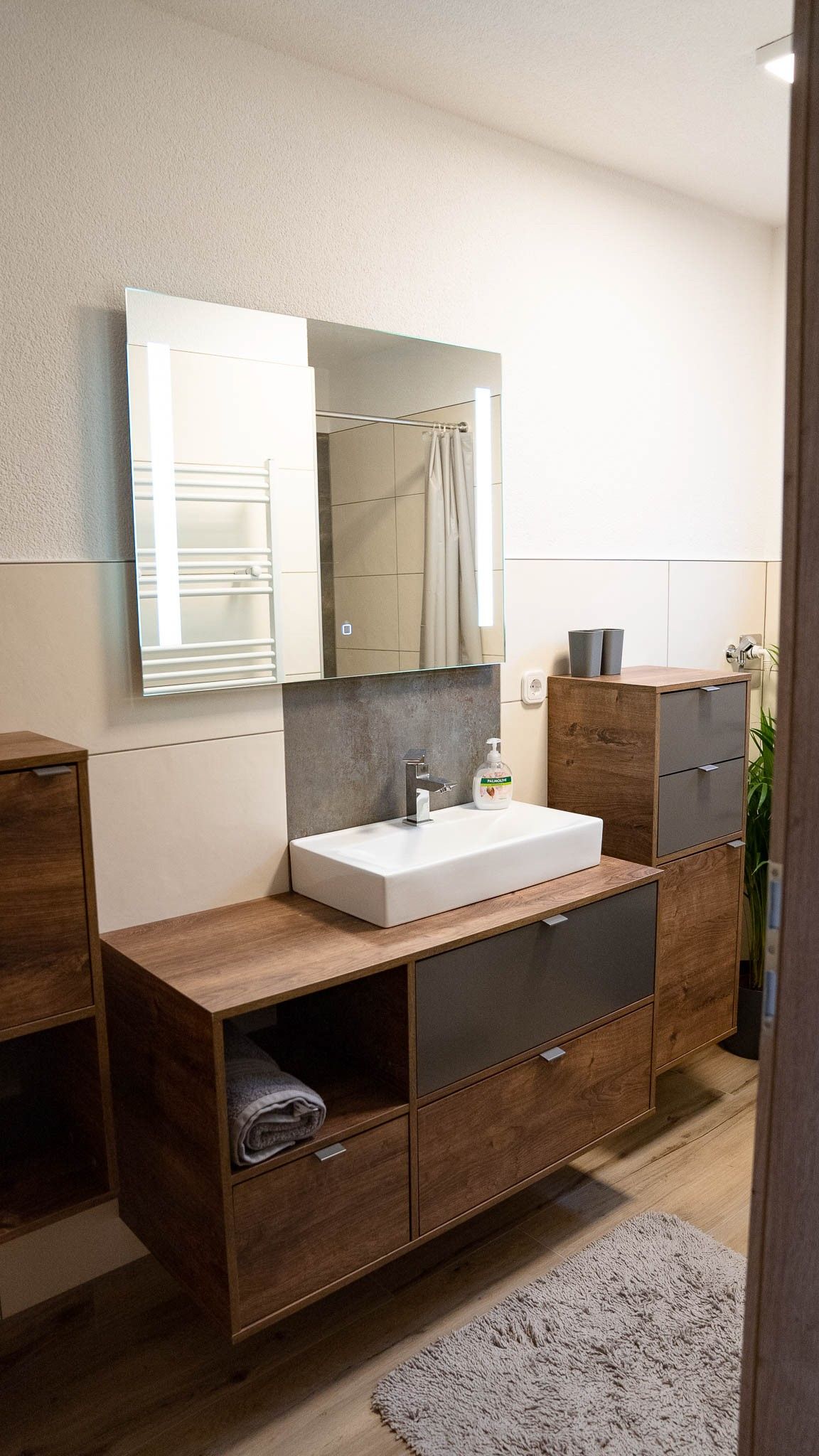 Modern bathroom with wooden cabinets, washbasin and mirror.
