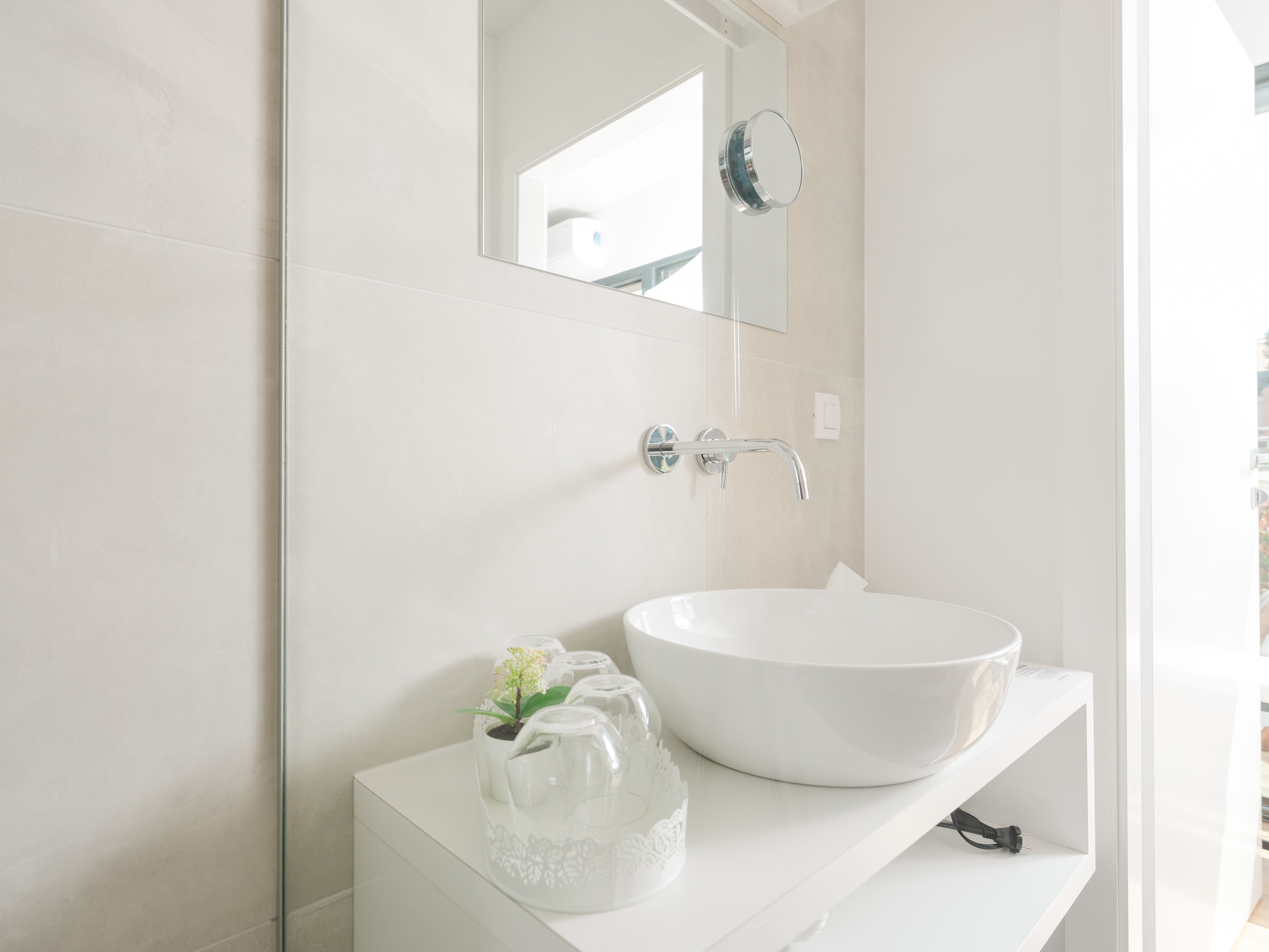 Modern bathroom with round washbasin and mirror.