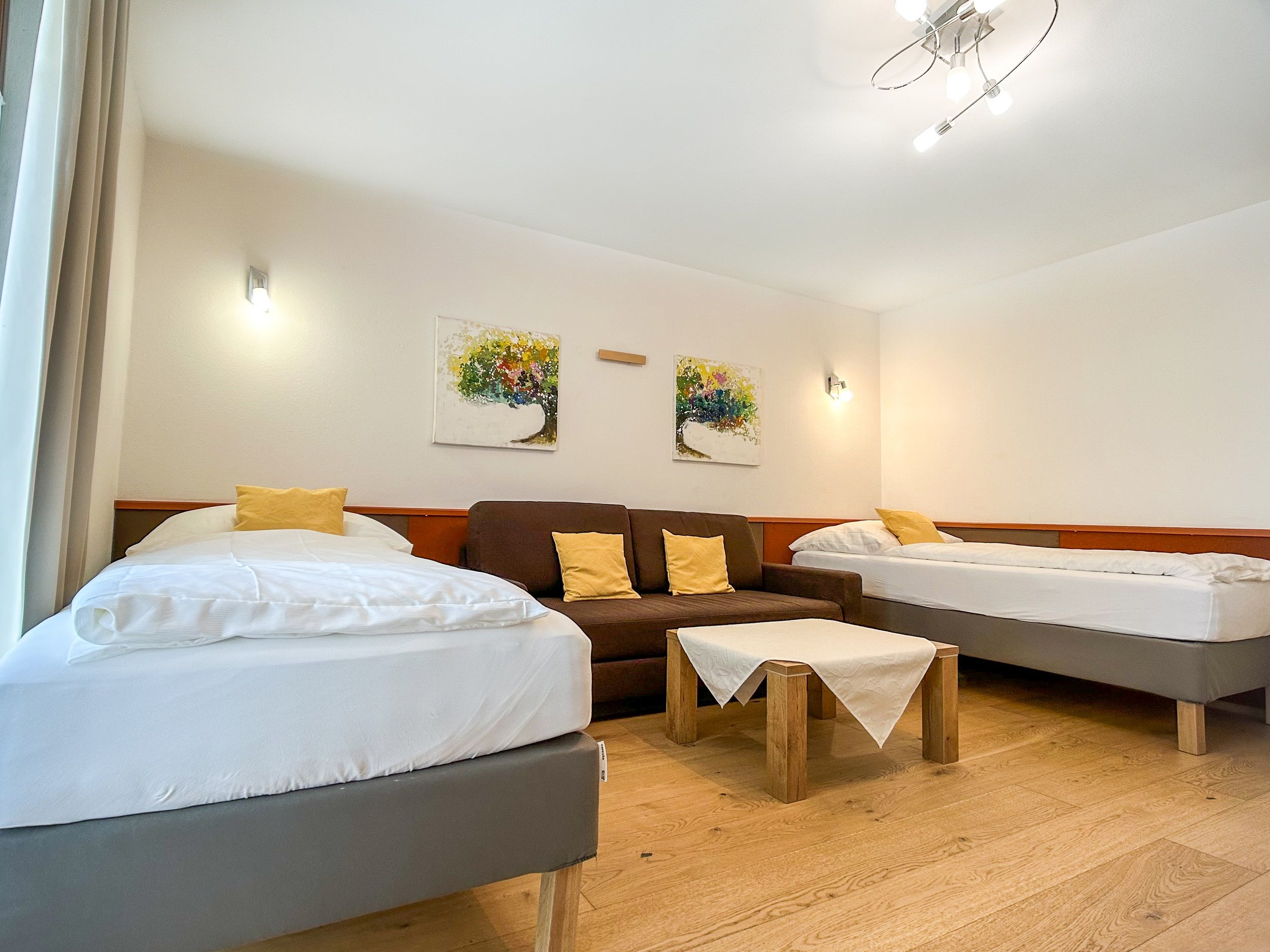 Bedroom with two beds, sofa and table.