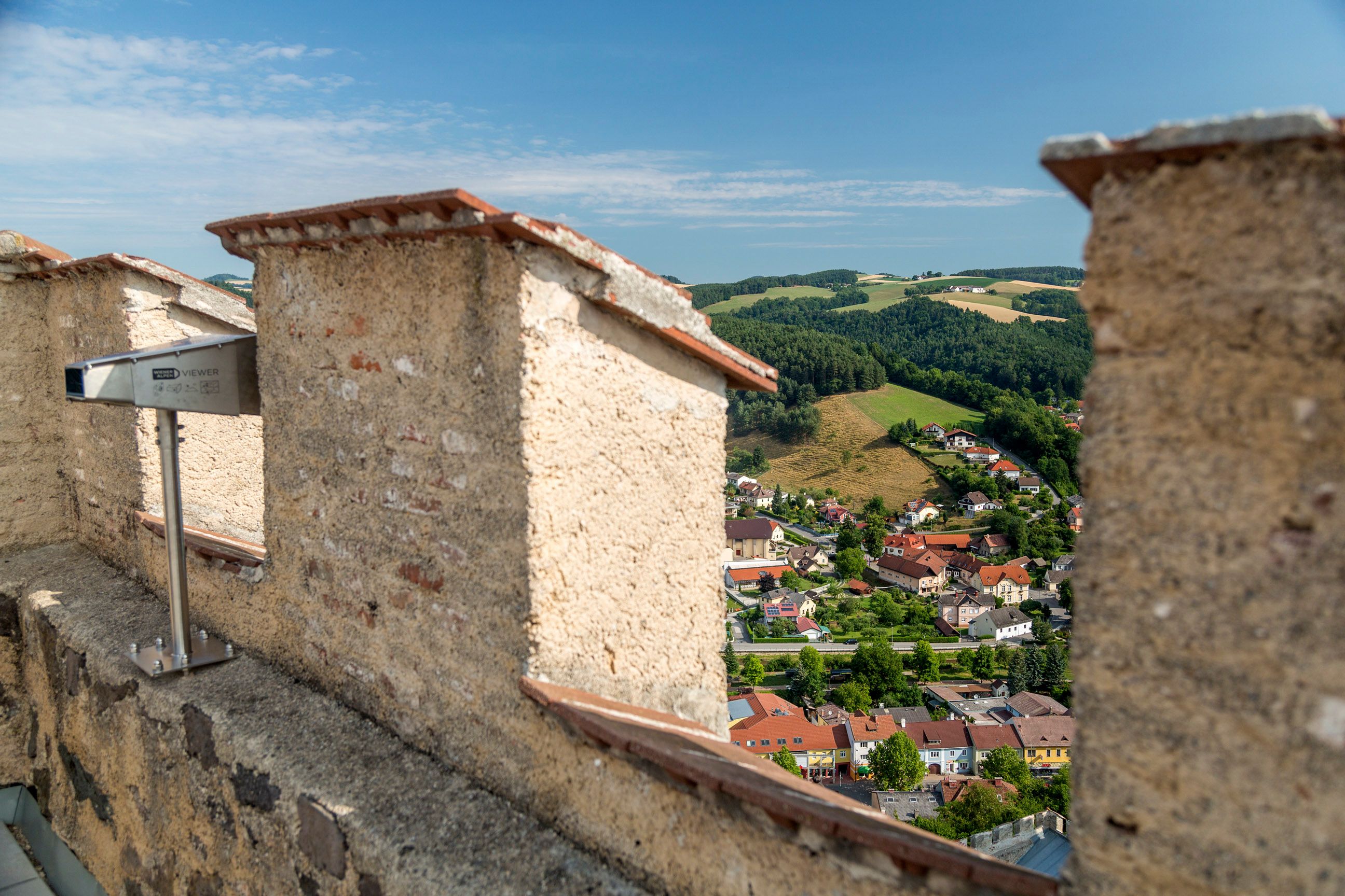 View of a town and green hills from a ruined castle.