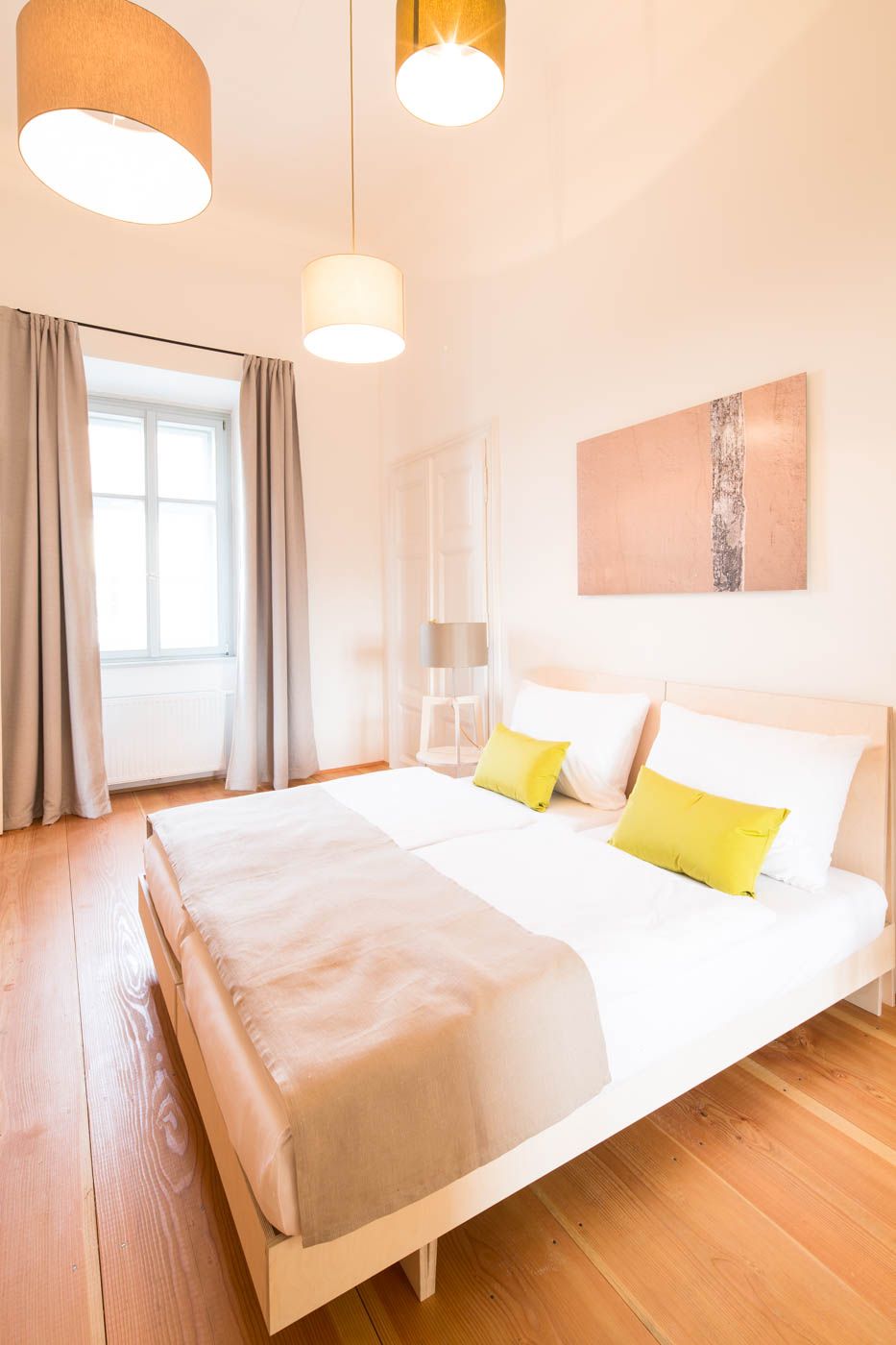 Bright bedroom with double bed, wooden floor and modern lamps.