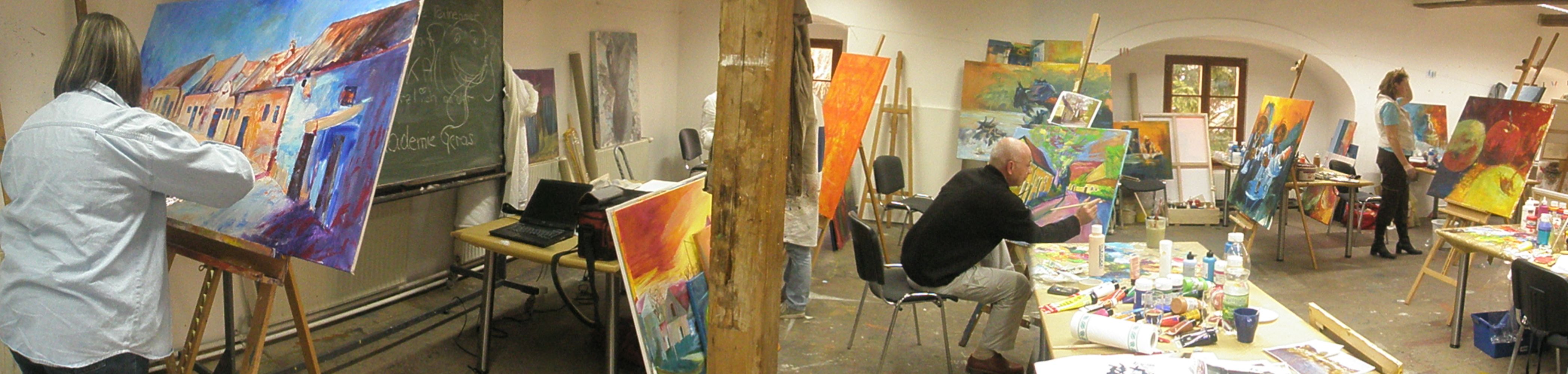 People paint in a studio with easels and colorful paintings.