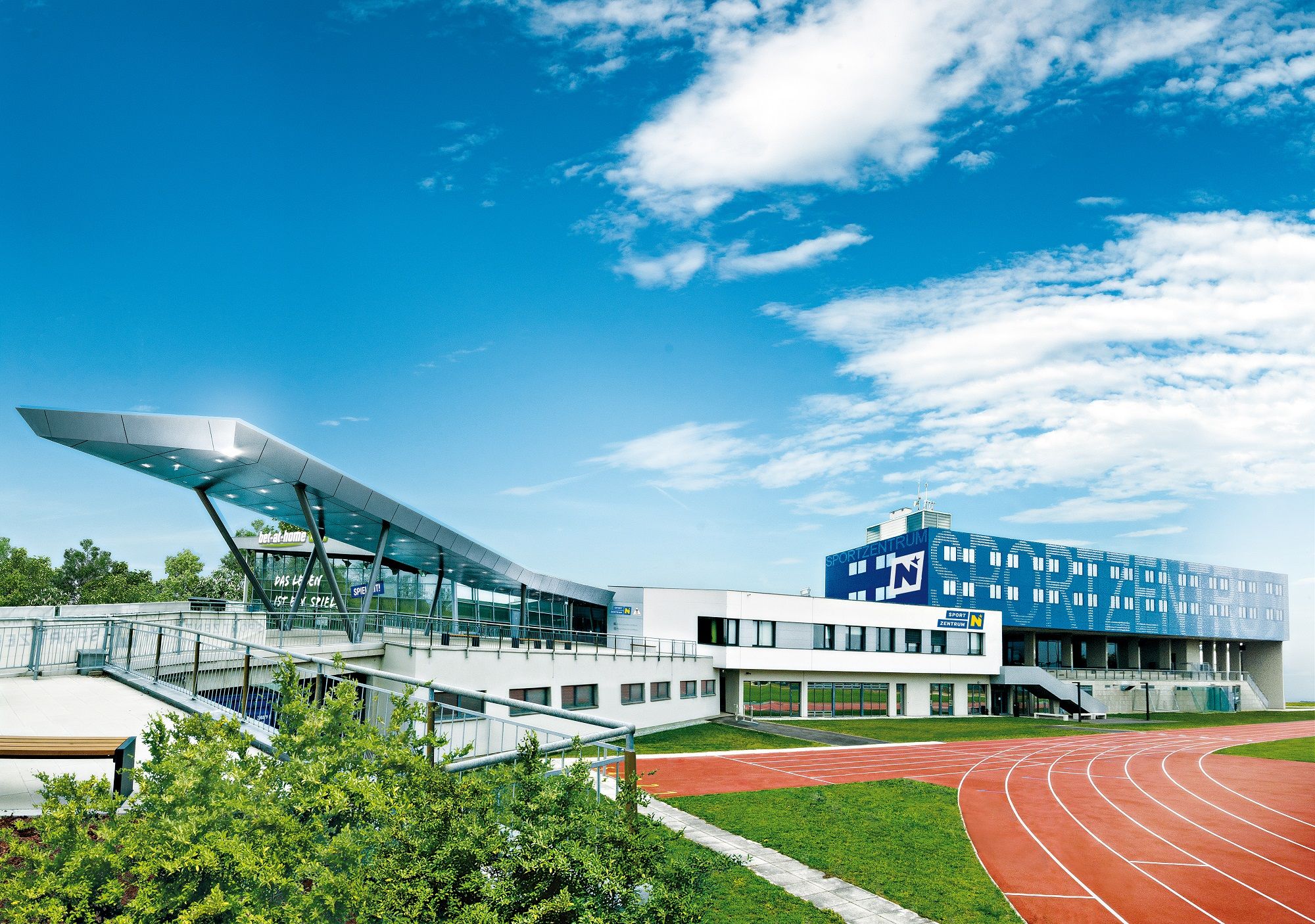 Modern sports center with running track and blue sky.