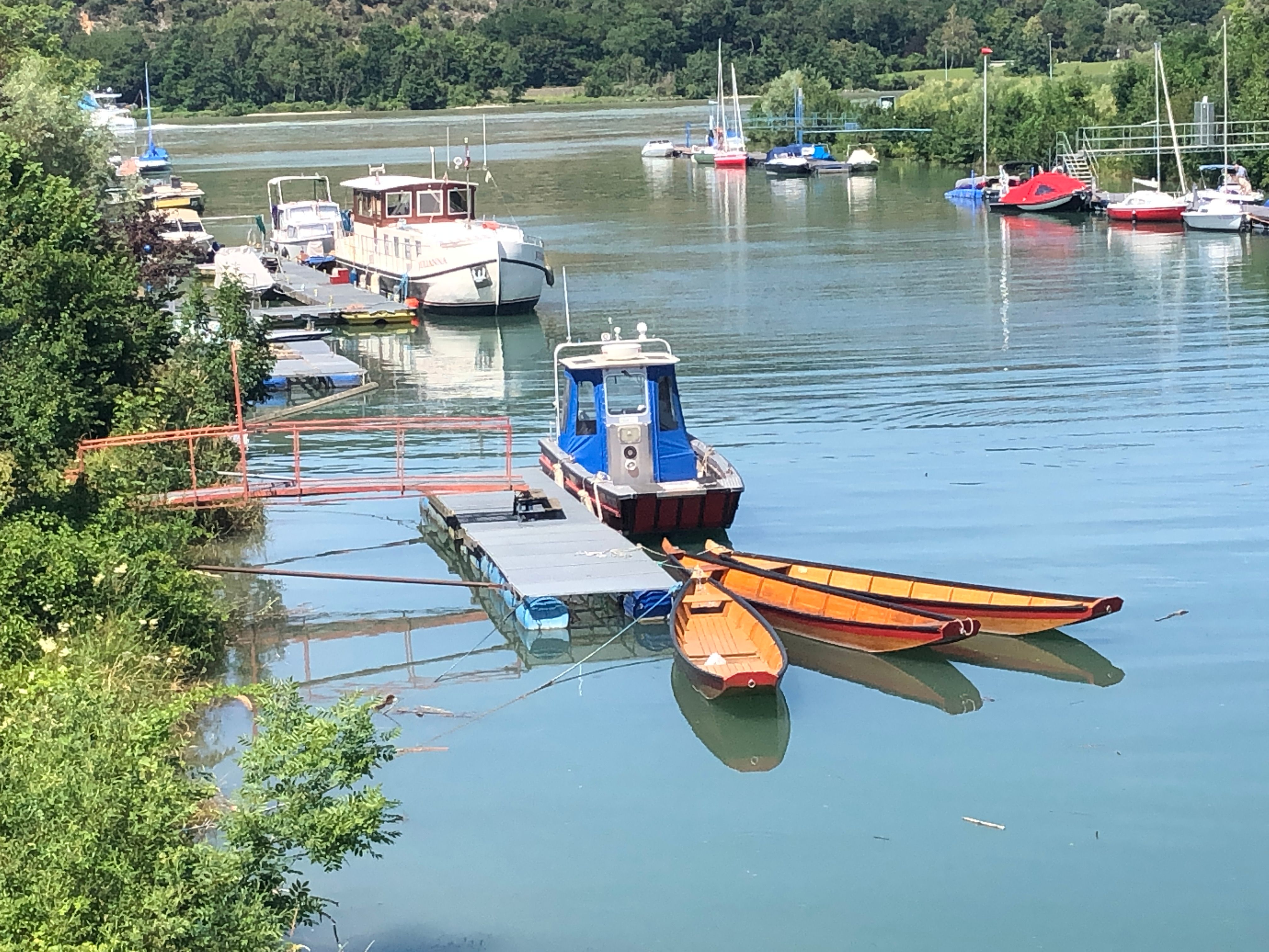 Boats on a jetty in a quiet harbor with green surroundings.