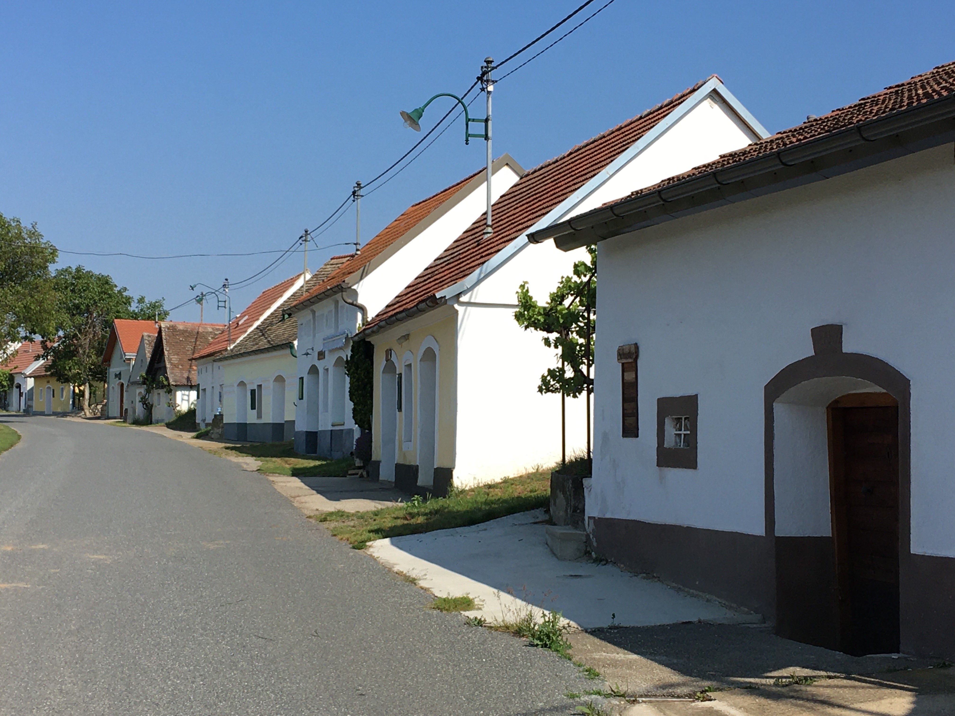 A quiet street with traditional whitewashed houses and red roofs in a rural setting.