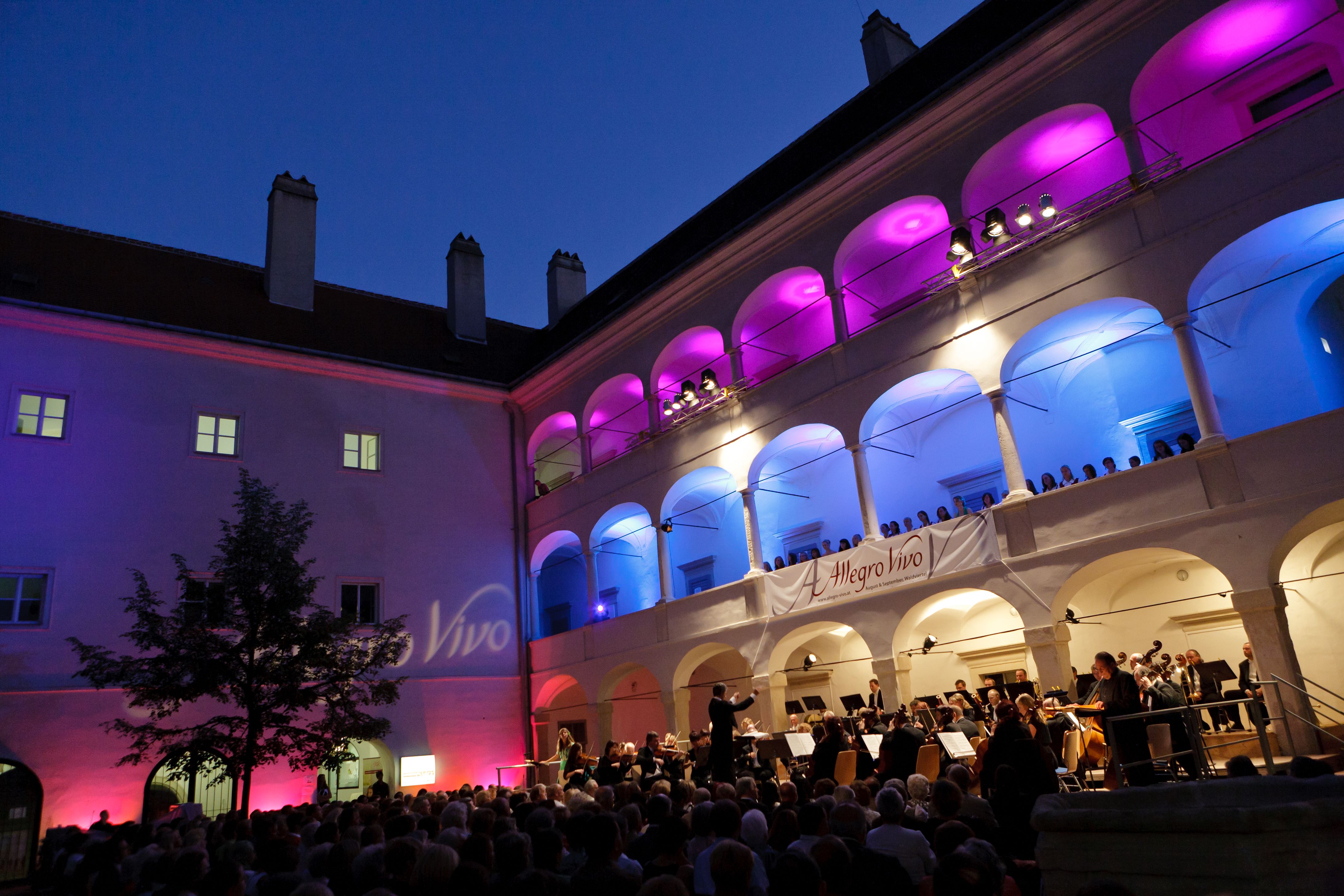 Concert in the arcade courtyard of the Kunsthaus Horn at night with colorful lighting.