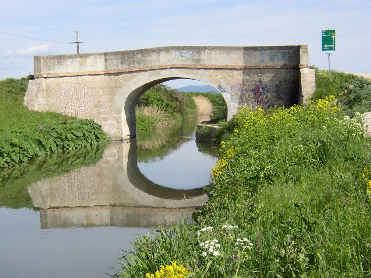 Bridge over the Wiener Neustädter Canal in Eggendorf with graffiti and reflection in the water.
