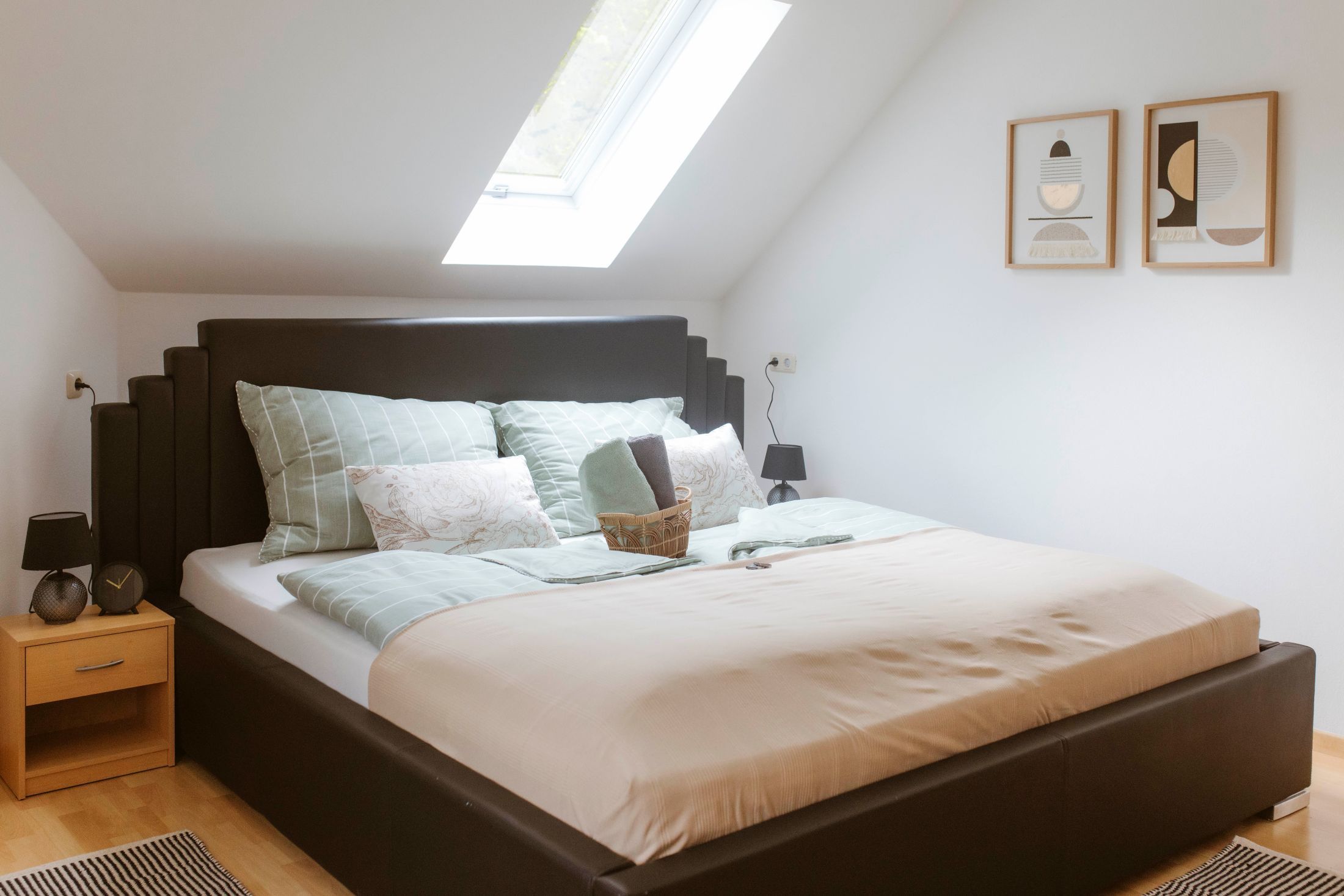 Cozy double room with skylight, modern bed and stylish decorations on the wall.