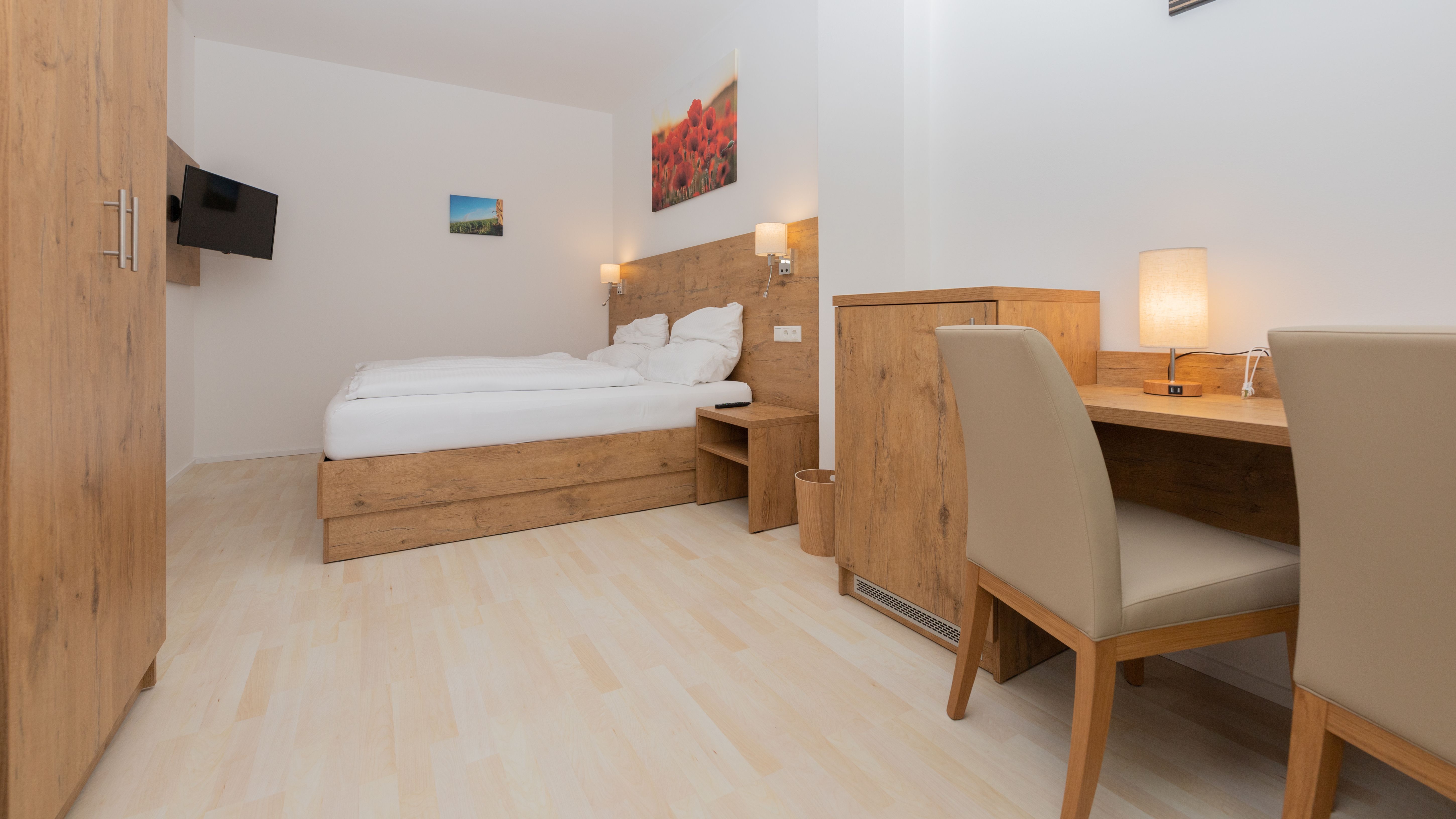 Modern bedroom with wooden furniture, double bed, desk and flat screen TV.