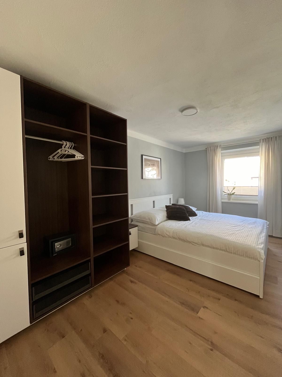Modern bedroom with double bed, closet and window with curtains.