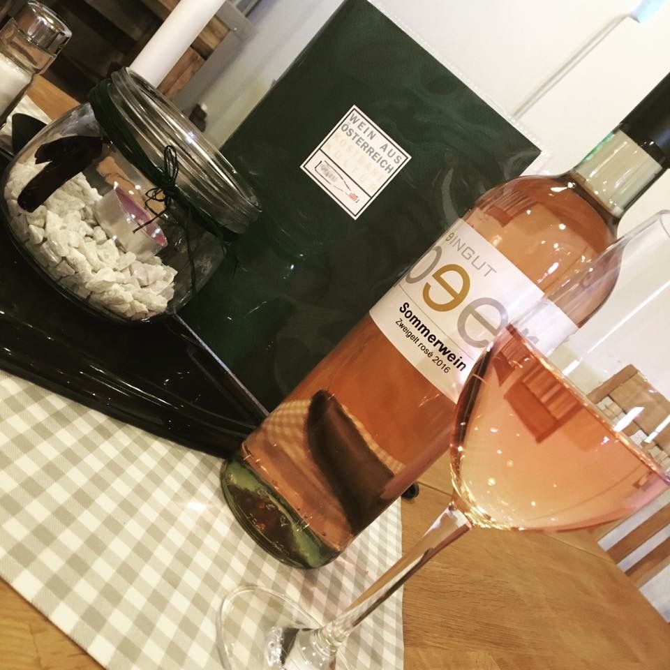 A bottle of rosé wine and a filled wine glass on a table with decoration.