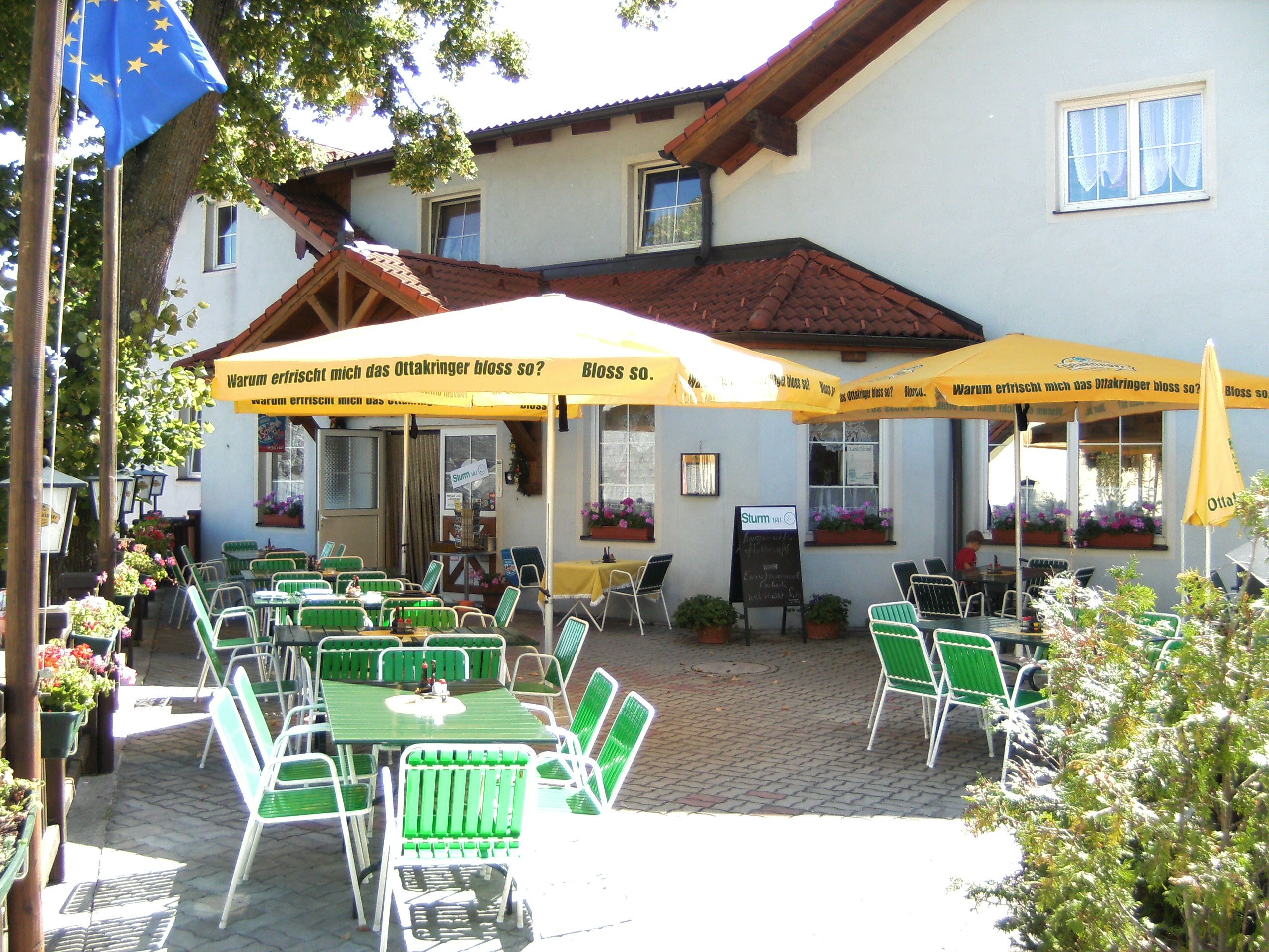 A garden with green chairs and yellow parasols in front of a building.