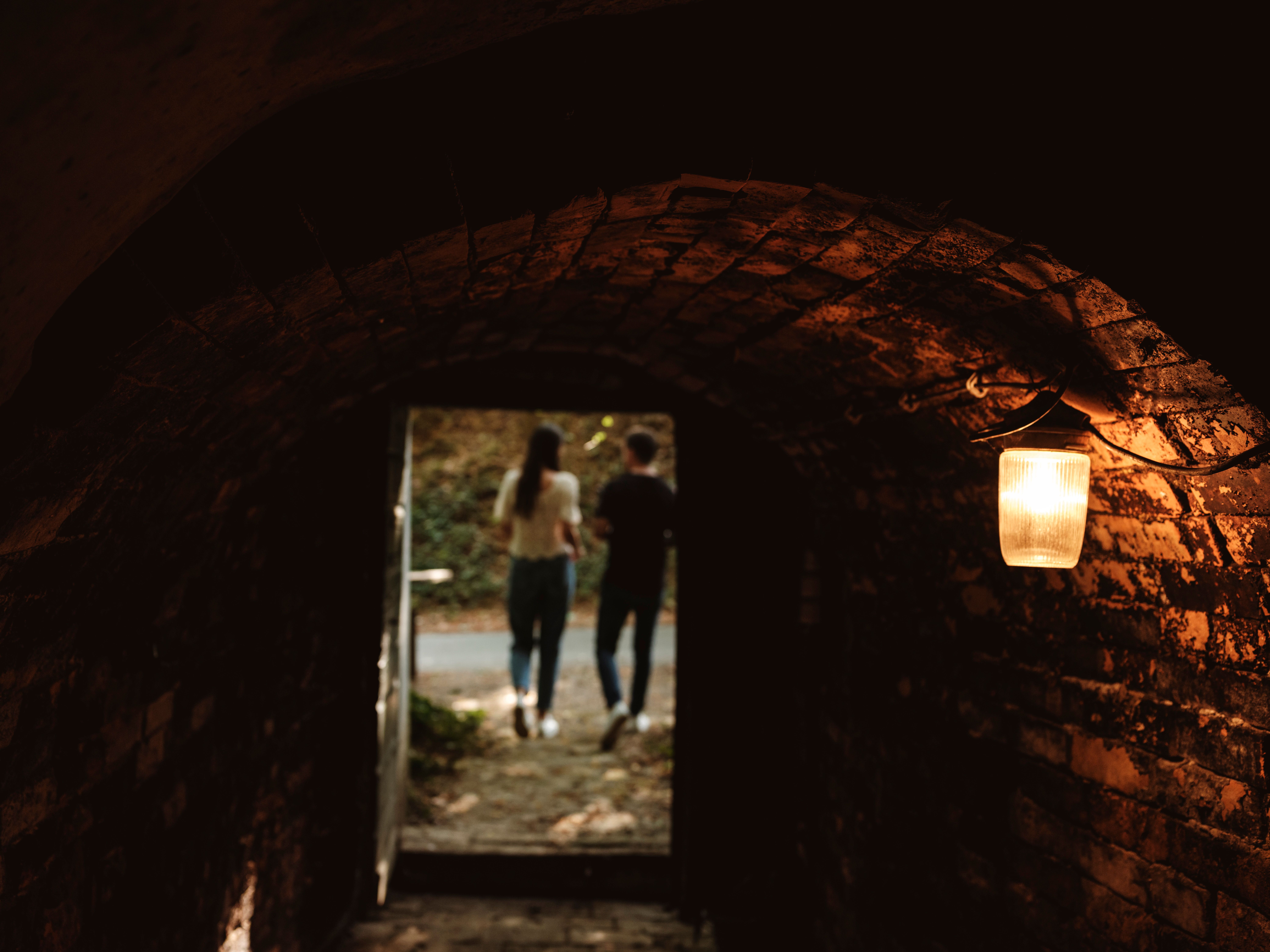 View from a dark tunnel of two people outdoors.