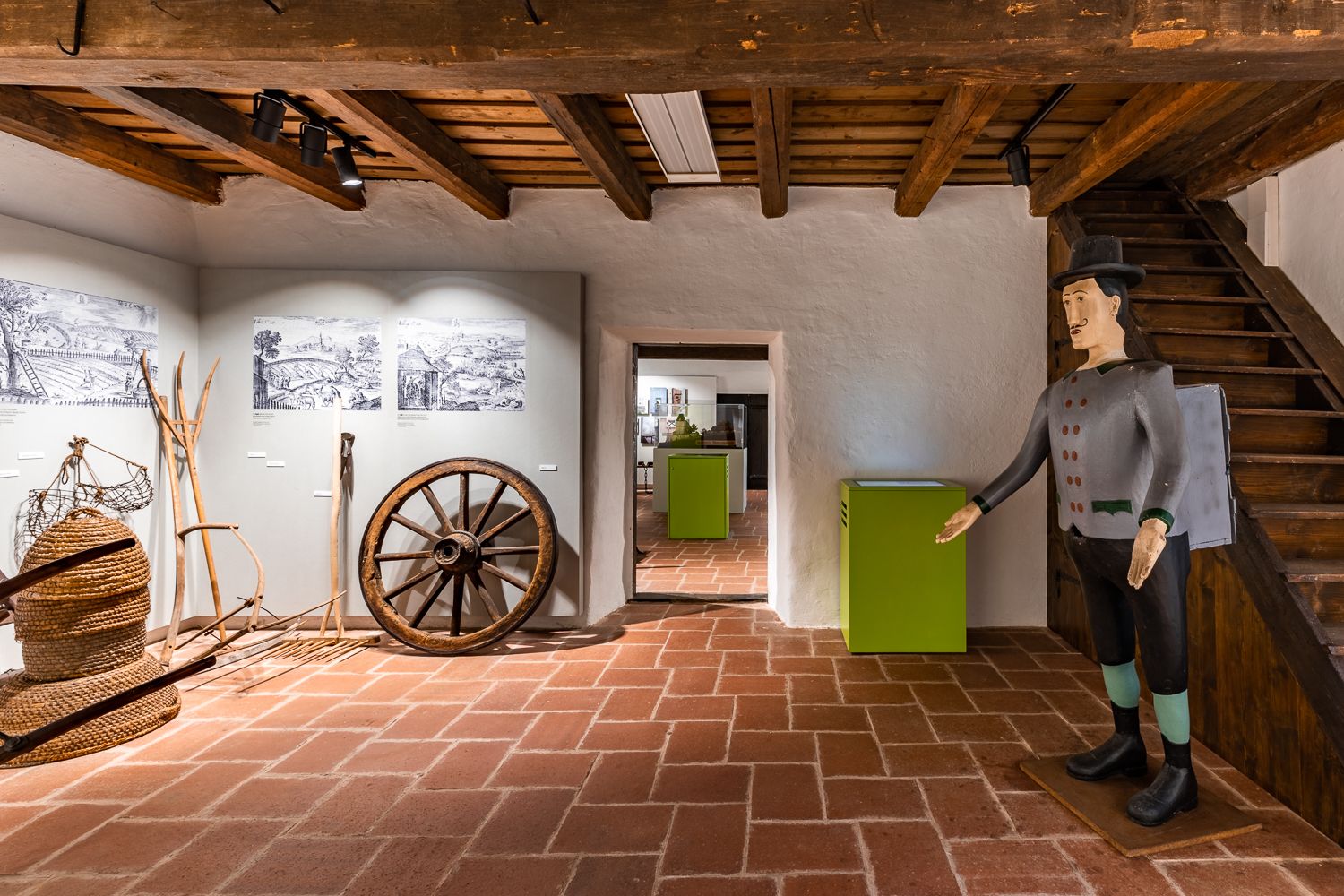 Interior view of a museum with old agricultural tools and a wooden figure.