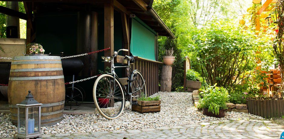 Rustic entrance area with bicycle, wooden barrel and plants.