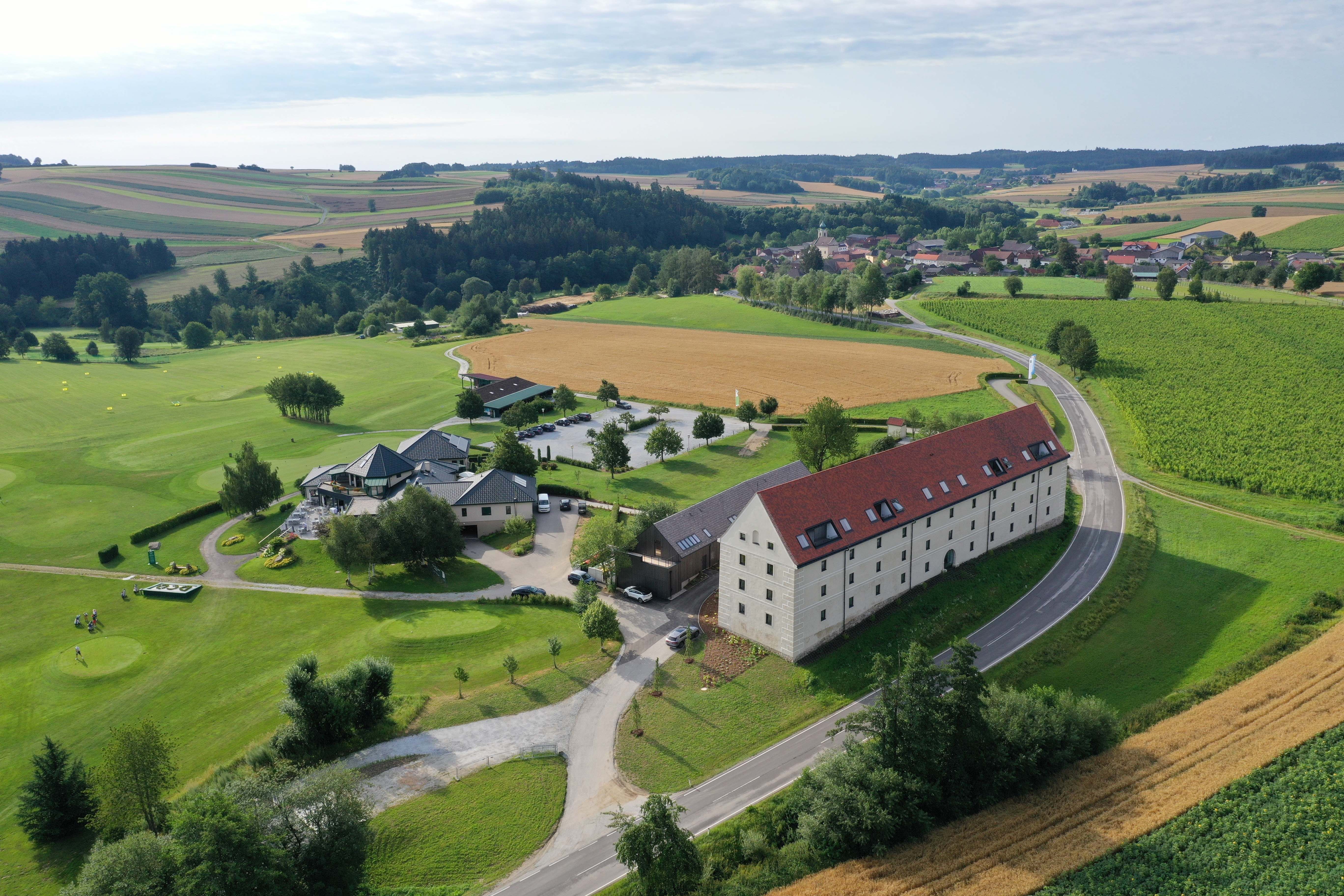 Aerial view of a country estate with golf course, fields and buildings in a rural setting.