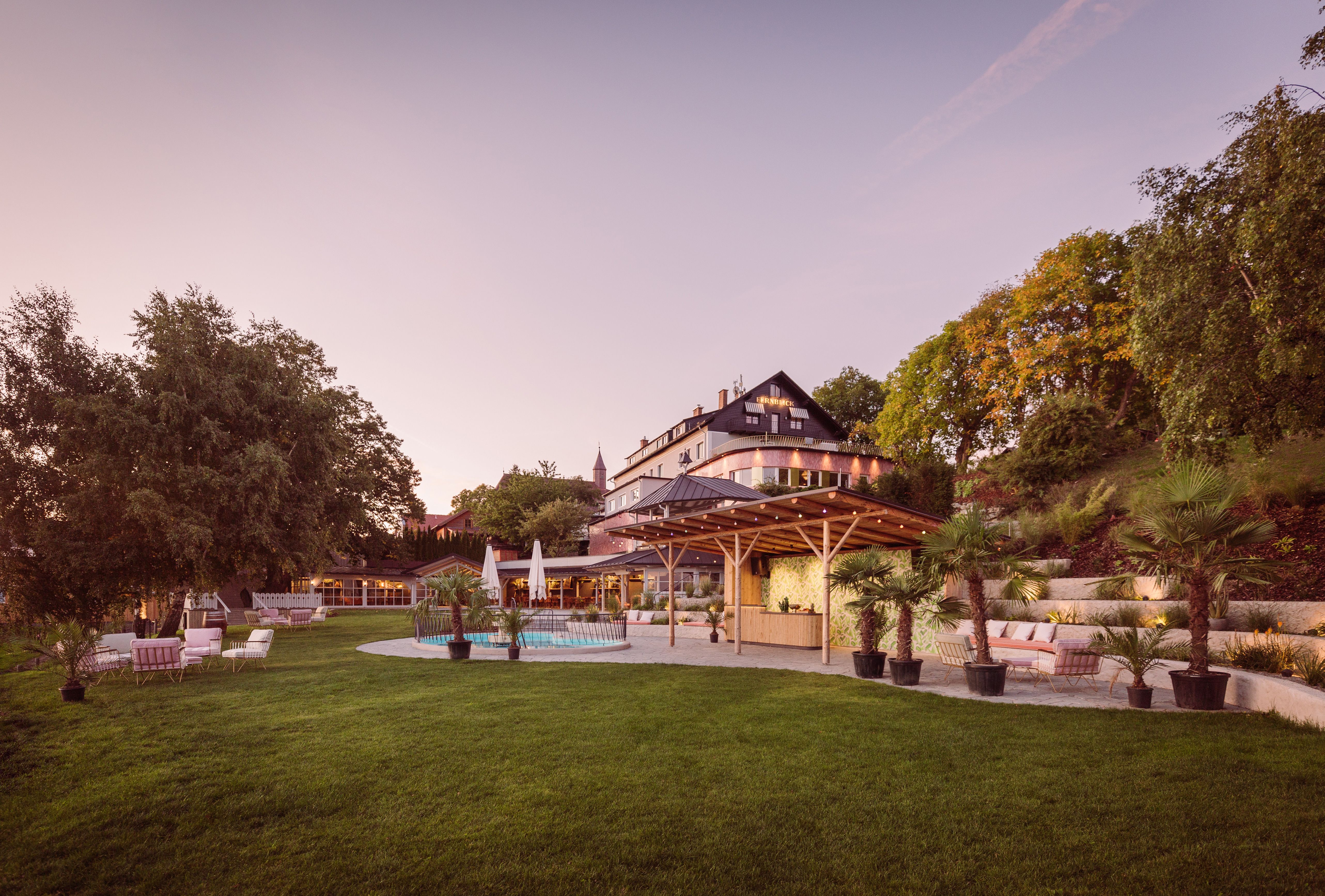 A large building with terrace and garden at sunset.