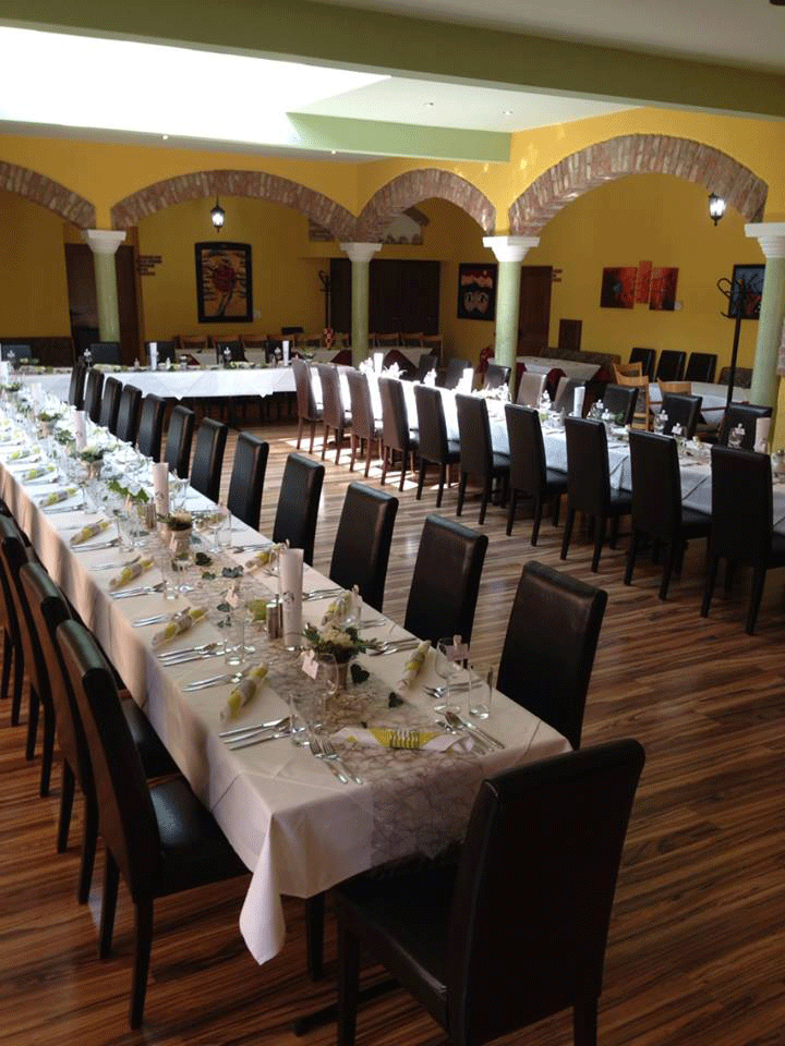 Festively decorated wedding table in a room with yellow walls and brick arches.