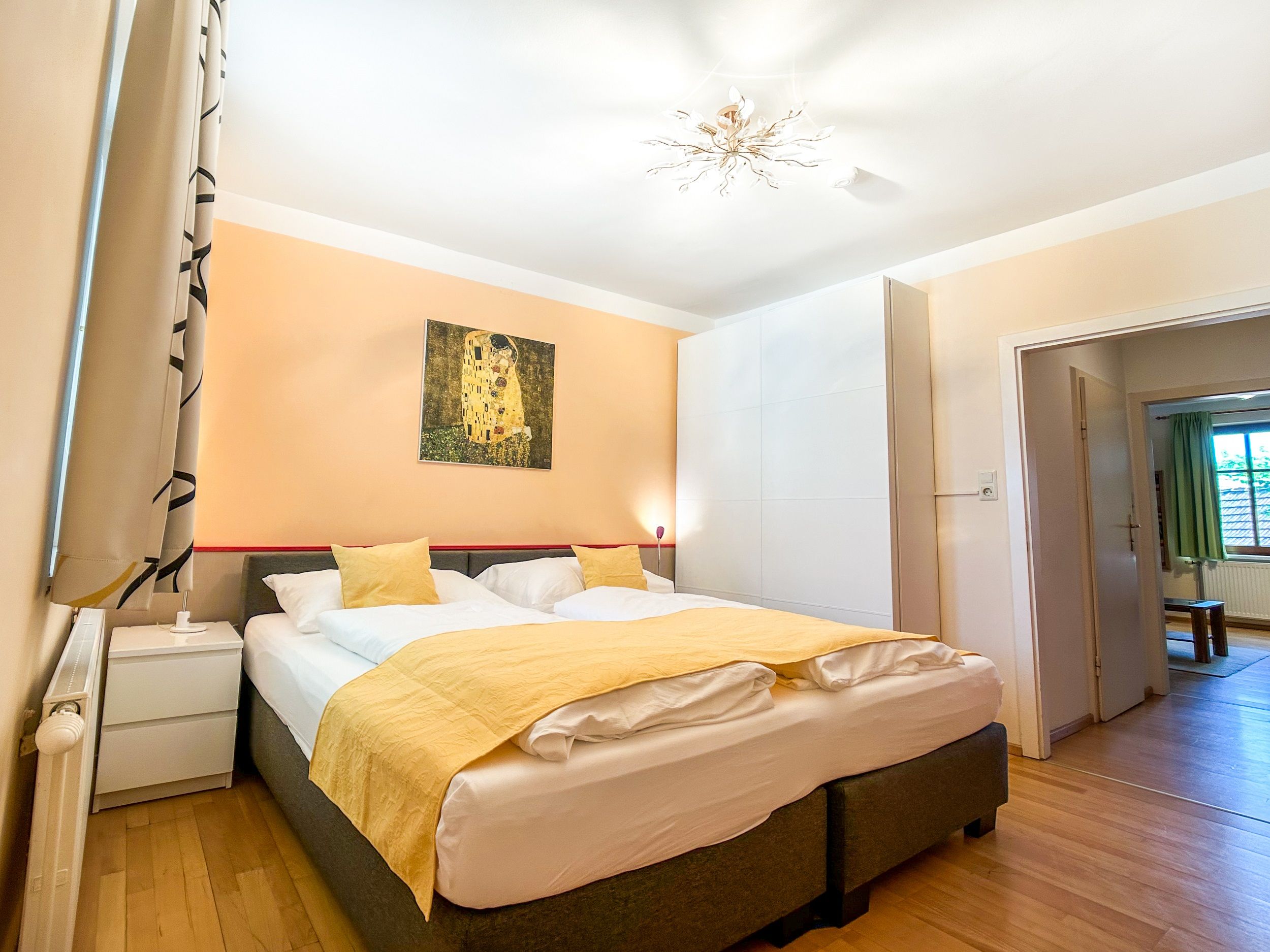 Bedroom with double bed, yellow bed linen and artwork on the wall.