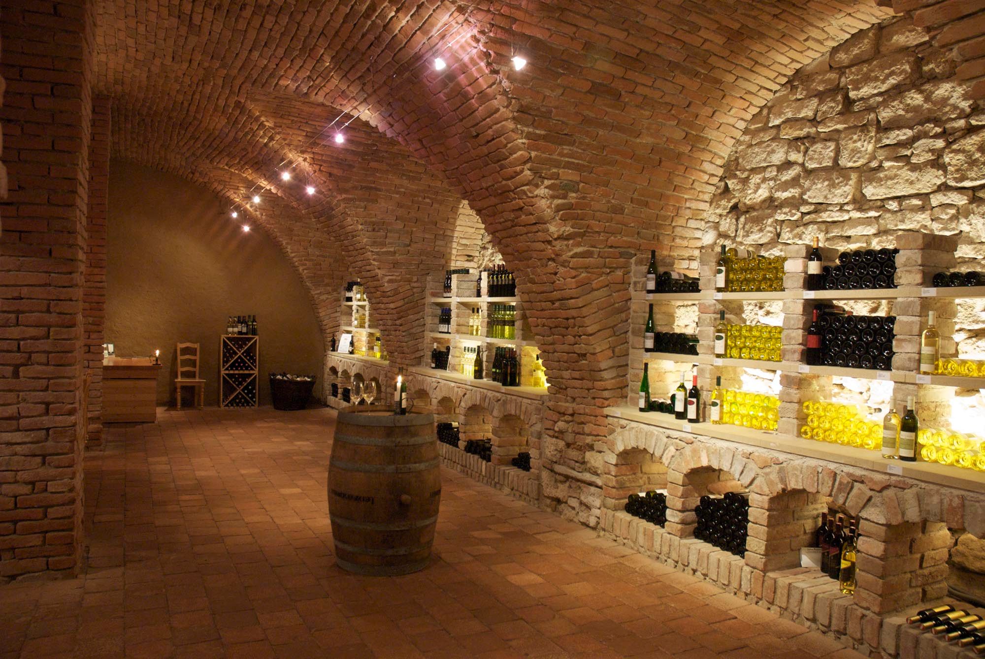 Wine cellar with brick vaults and wine bottles on shelves.