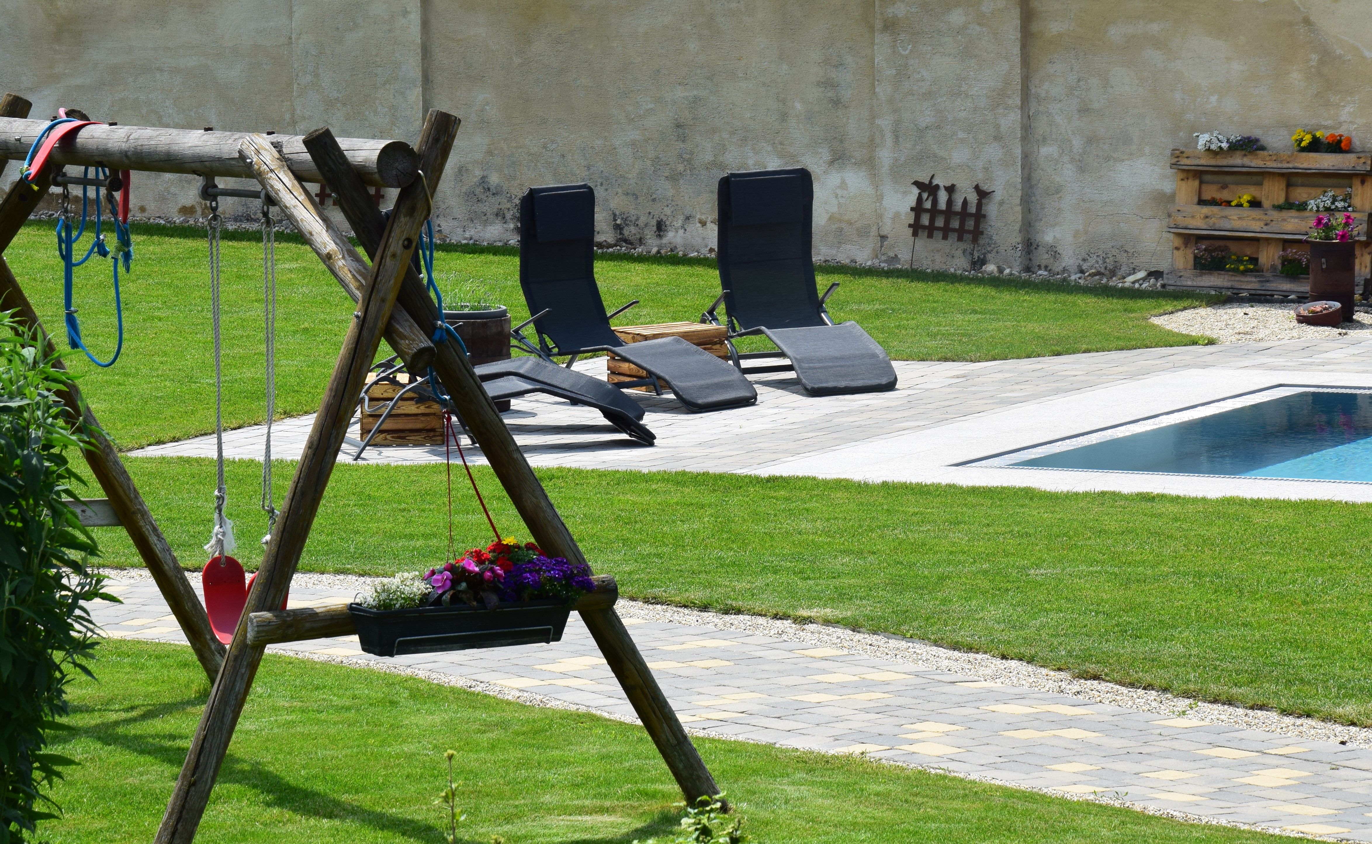 Garden with swing, sun loungers and pool.