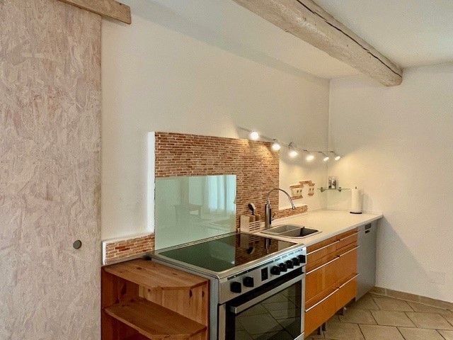 Modern kitchen with wooden cupboards, stove, sink and tiled splashback.