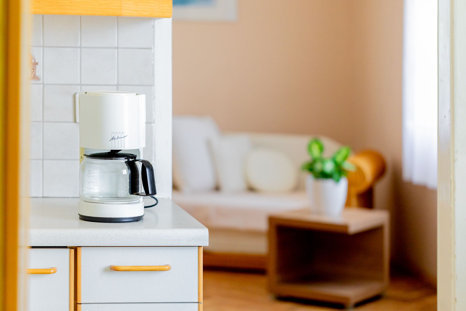 Coffee machine on kitchen counter with living room in the background.