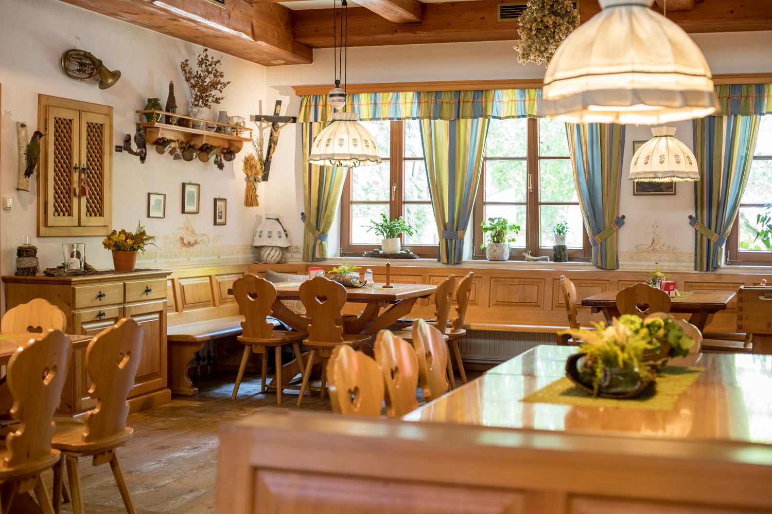 Cozy dining room with wooden furniture, decorative lamps and plants on the tables.