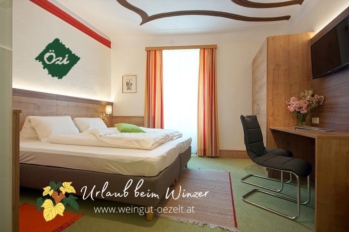 Cozy guest room with double bed, desk and chair, decorated with flowers. Light-colored curtains and carpeted floor.